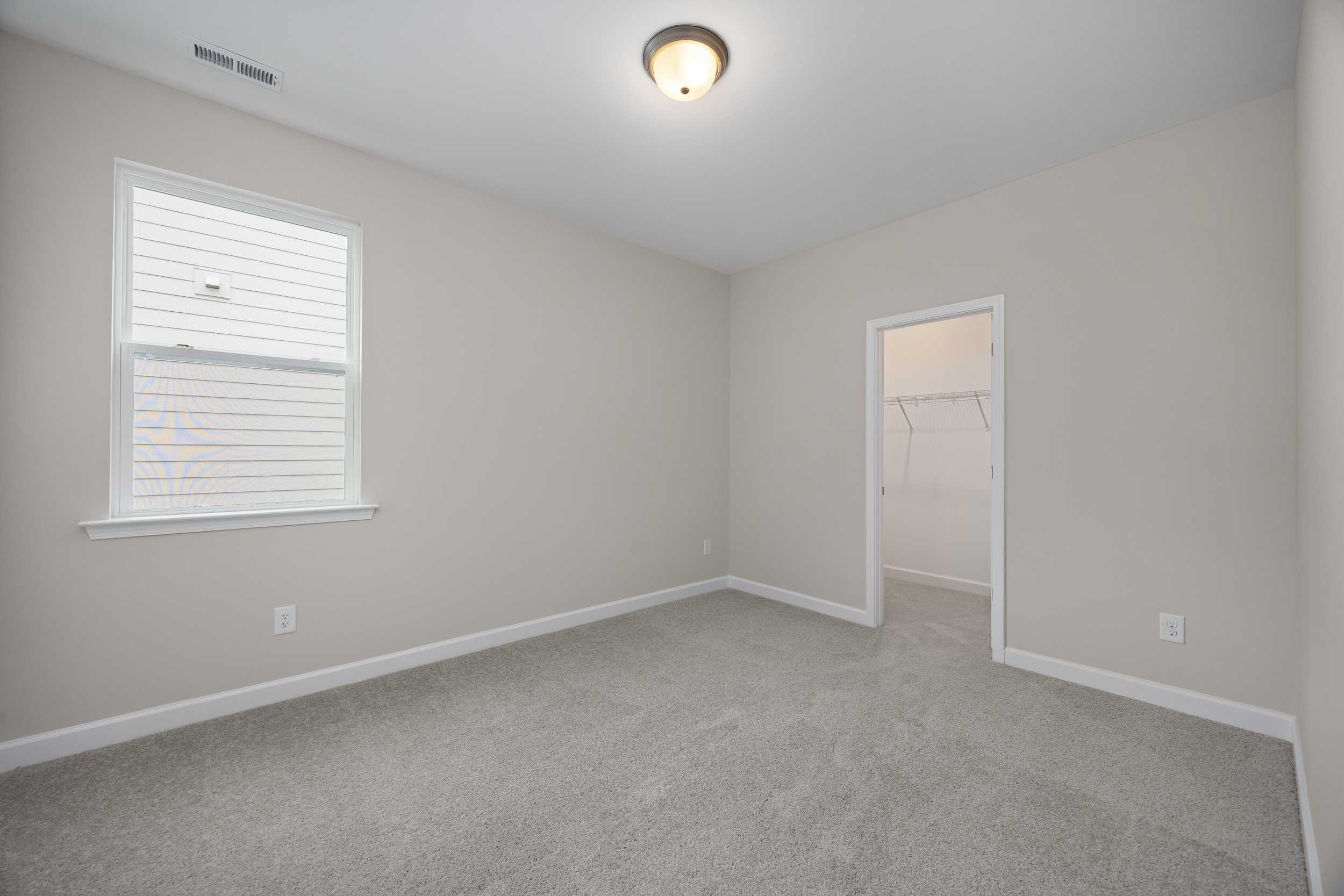 Spacious secondary bedroom in The Beech C featuring beige walls, carpeted floor, large window with blinds, and open closet