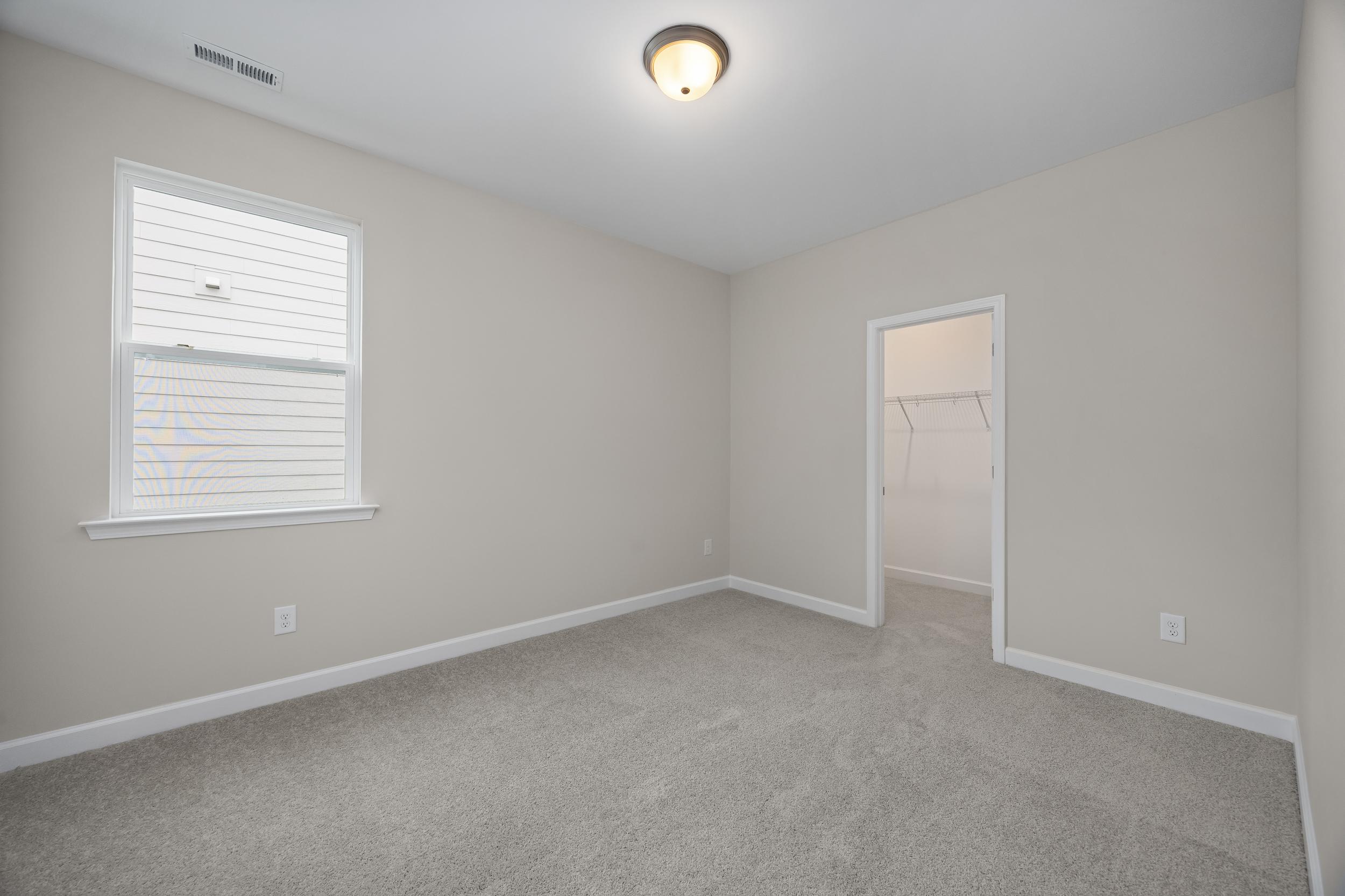 Spacious secondary bedroom in The Beech A with beige walls, gray carpet, large window blinds, ceiling light, and walk-in closet