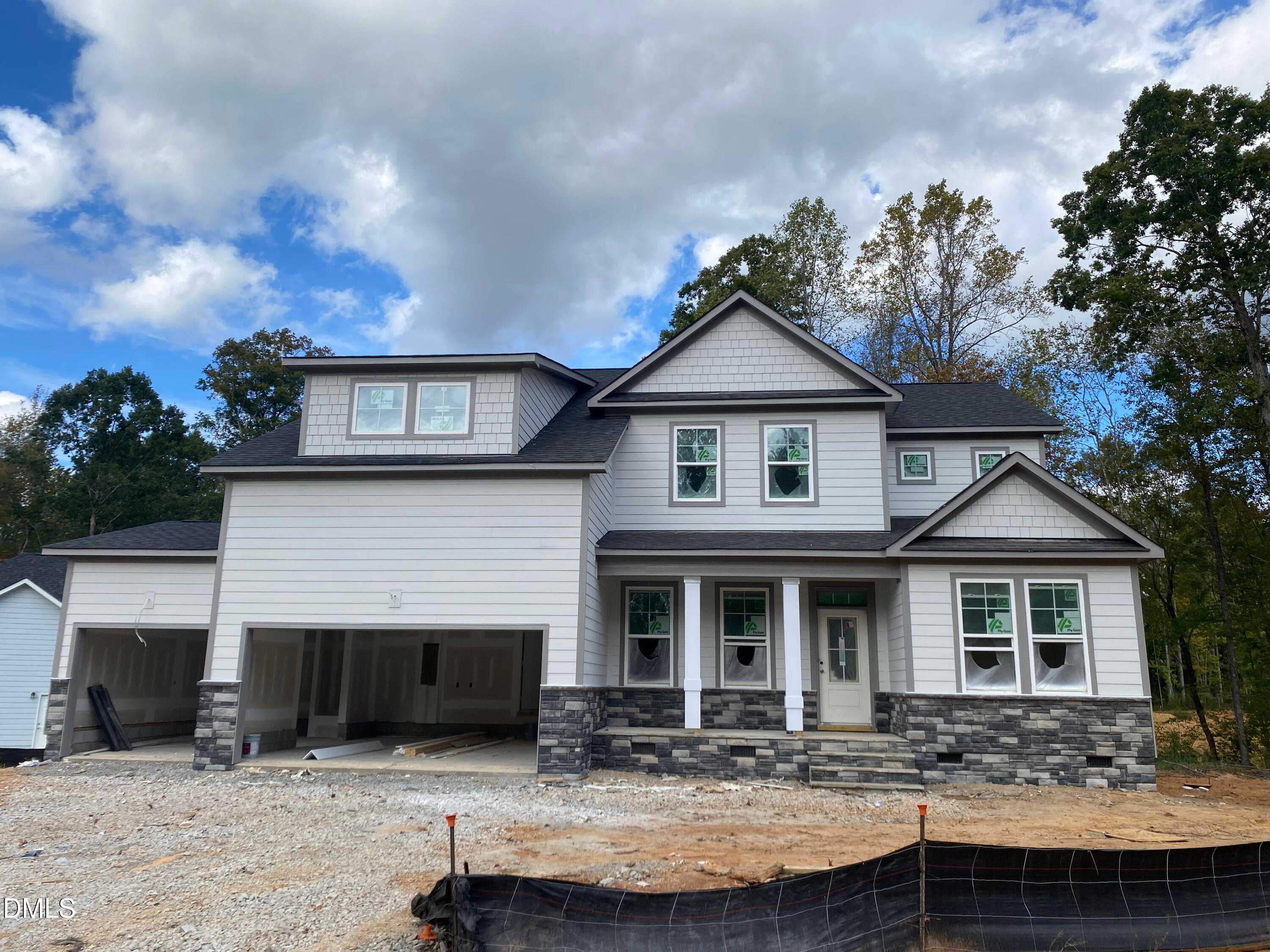 Modern two-story 4-bedroom home with open 3-car garage, columned porch, and wooded backdrop in Laneridge Estates, Raleigh, NC