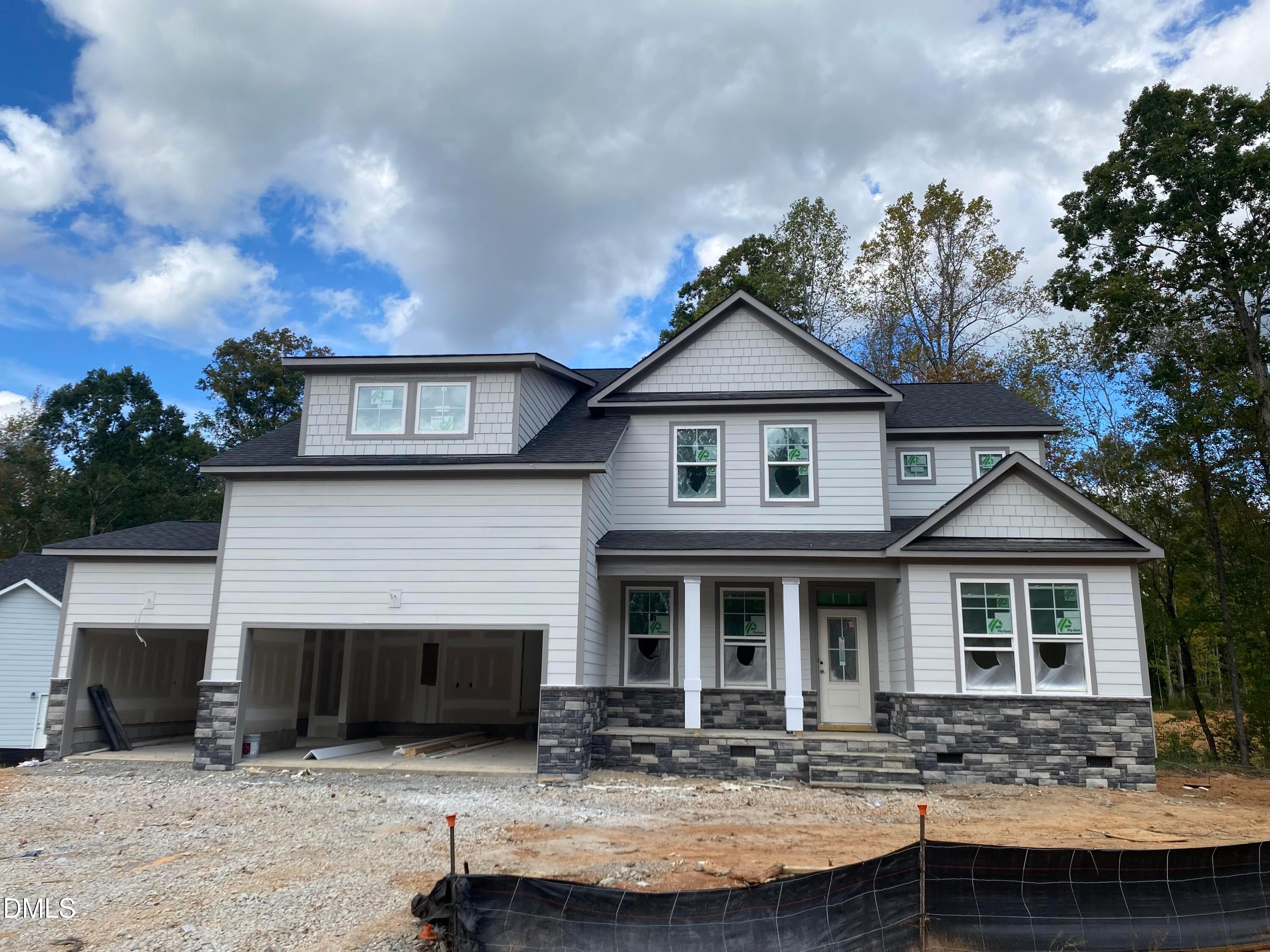 Modern two-story 4-bedroom home with open 3-car garage, columned porch, and wooded backdrop in Laneridge Estates, Raleigh, NC