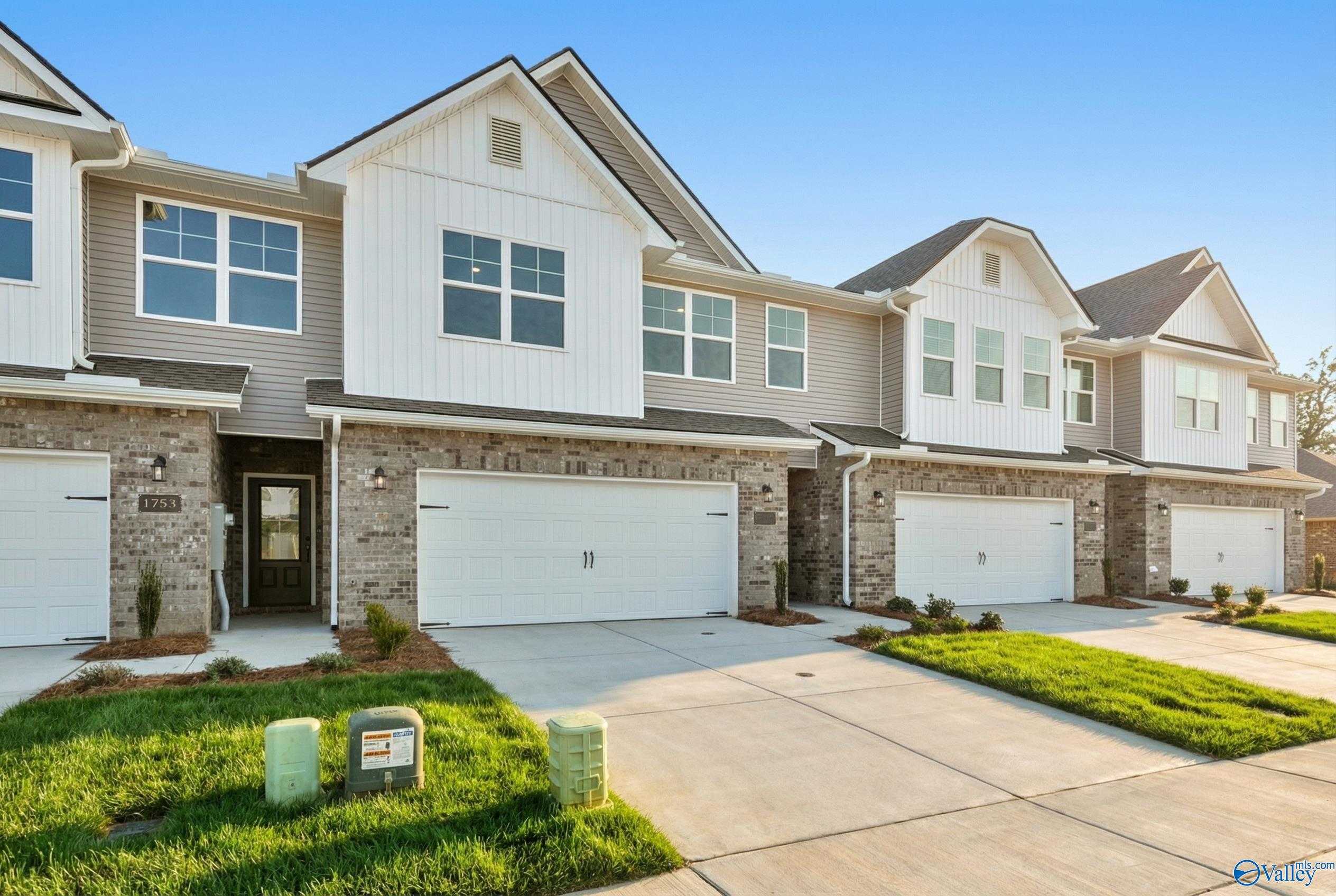 Modern two-story townhomes with two-car garages, brick accents, and landscaped driveways in Pavilion, Huntsville, Alabama