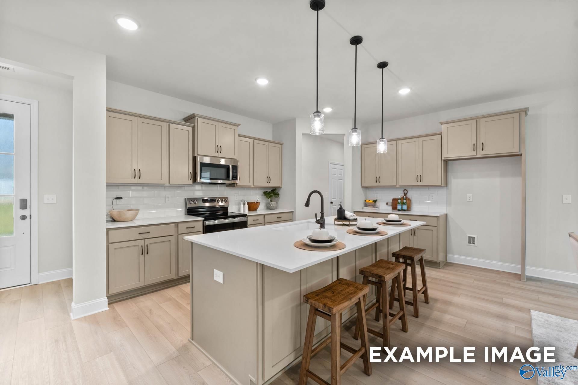 Modern open-concept kitchen with beige cabinets, quartz island, stainless appliances in Davidson Homes The Kirkland, Decatur, AL