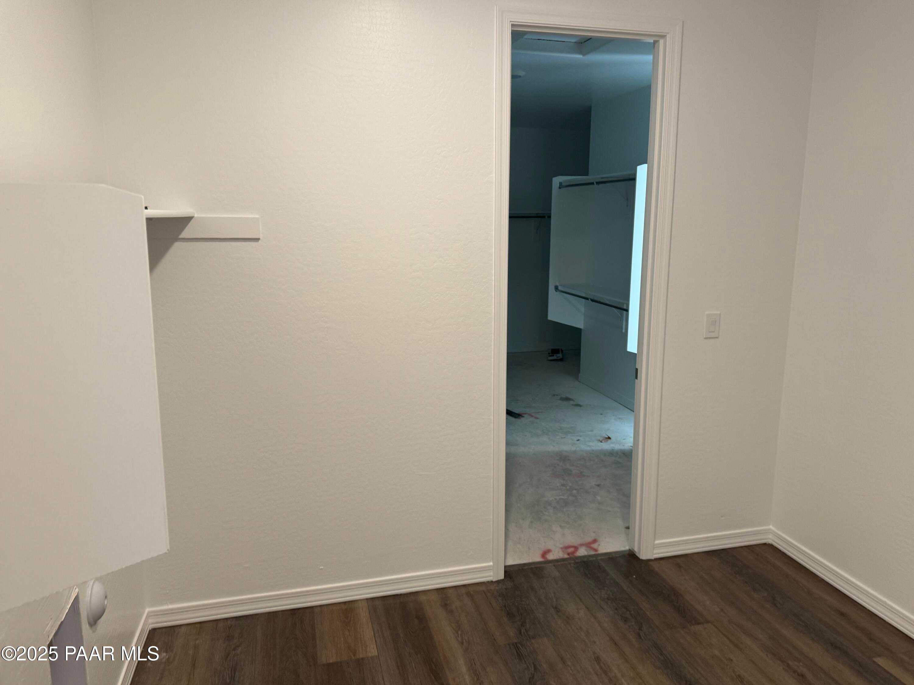 Spacious empty bedroom with open walk-in closet, white built-in shelving, hardwood floors in Davidson Homes Sunrise II A, Prescott AZ