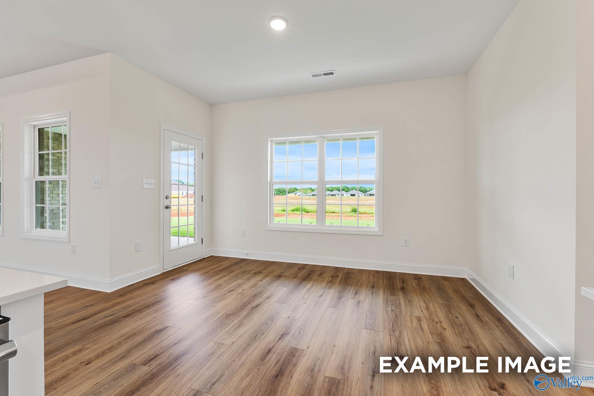 Bright great room with hardwood floors, French doors to patio, and large windows overlooking green fields in Davidson Homes The Emory, Toney, Alabama