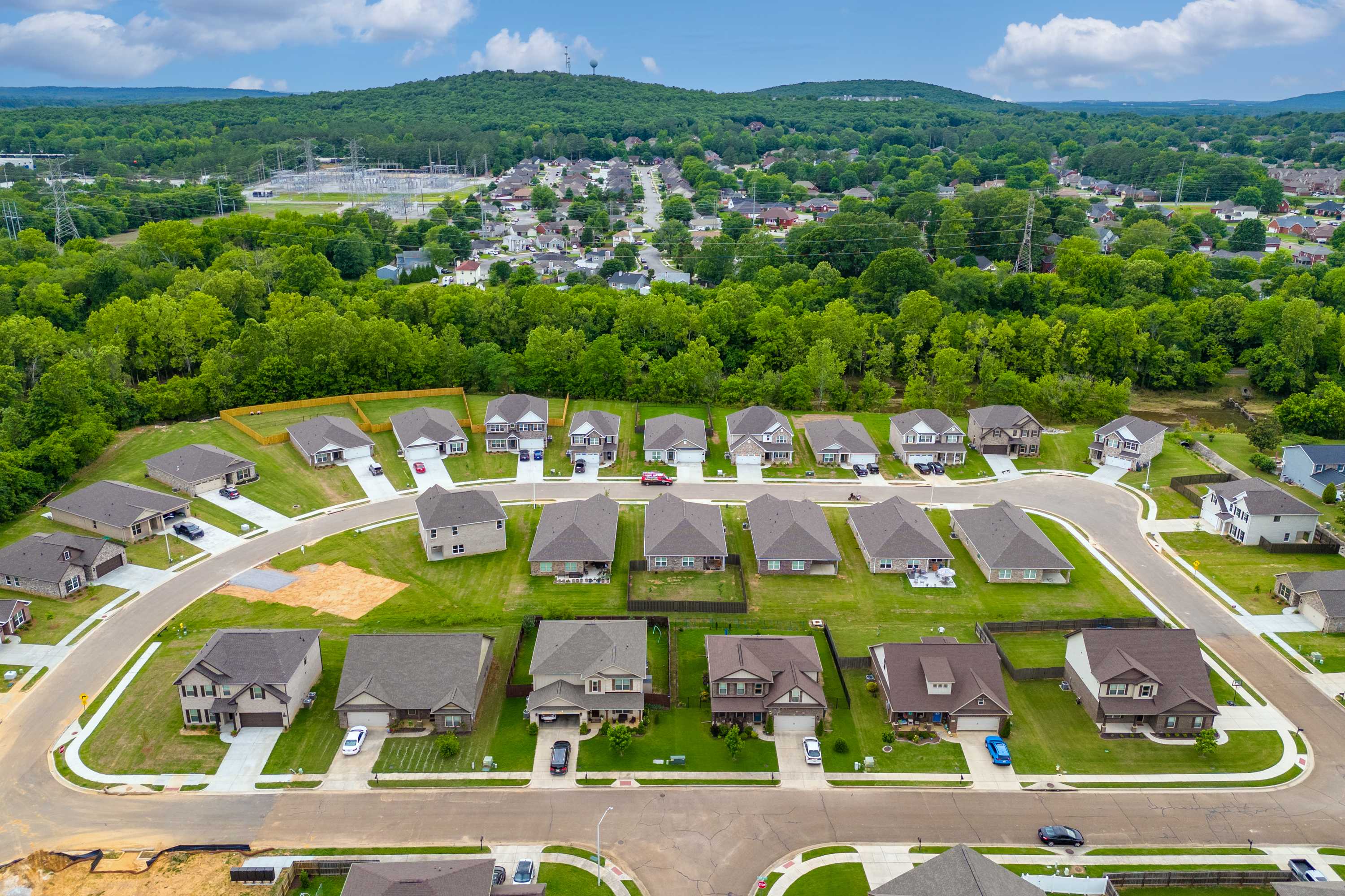 Aerial view of new homes in Pavilion neighborhood Huntsville AL with curved streets lush greenery and distant hills