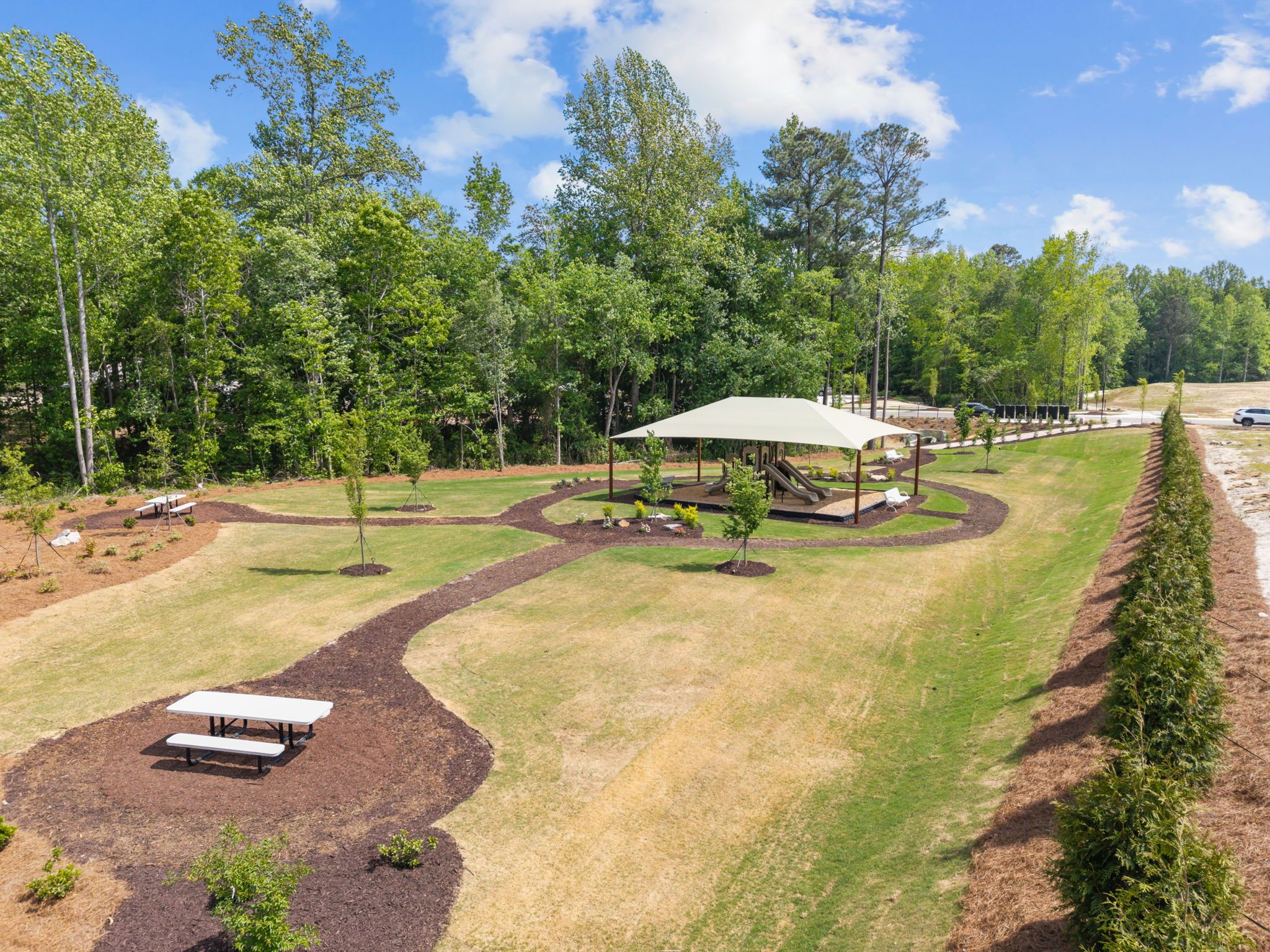 Community playground with shaded structure and picnic tables at Wendell Ridge in Wendell, NC by Davidson Homes.