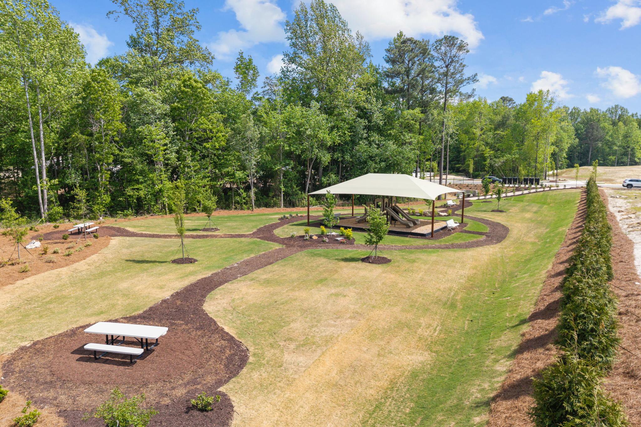 Community playground with shaded structure and picnic tables at Wendell Ridge in Wendell, NC by Davidson Homes.