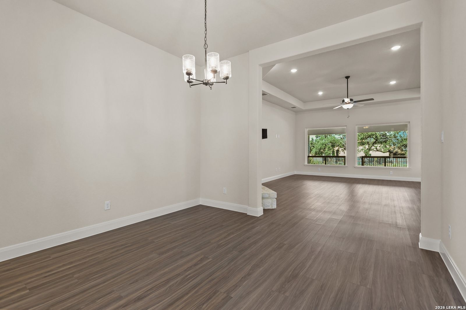 Formal dining room with chandelier flowing into an open-concept living area in Davidson Homes Summerlin B, Castroville, TX.