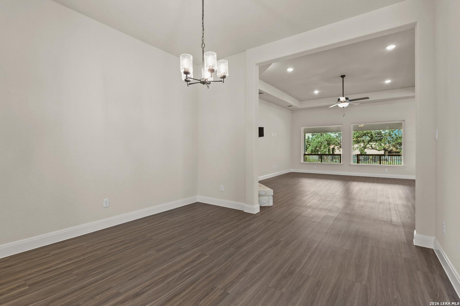 Formal dining room with chandelier flowing into an open-concept living area in Davidson Homes Summerlin B, Castroville, TX.