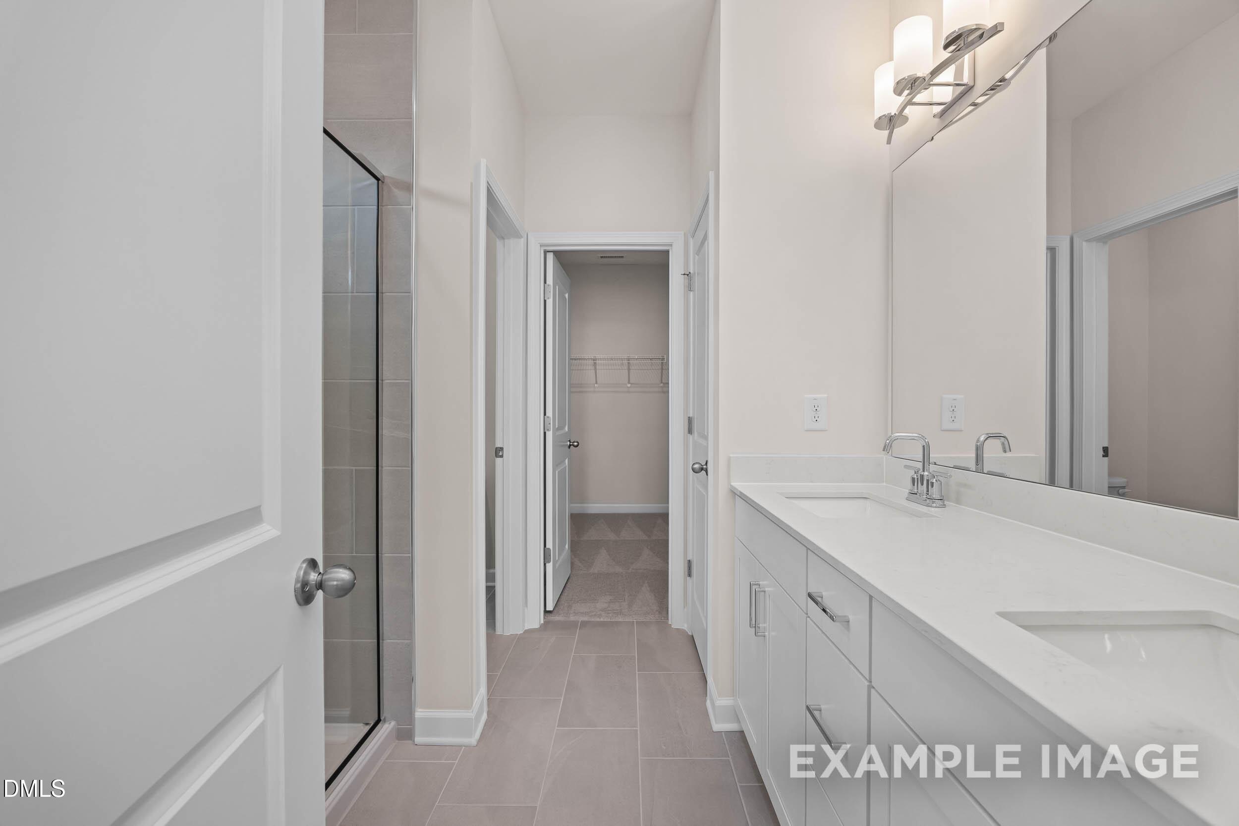 Modern bathroom with dual vanity and glass-enclosed shower in The Franklin C floor plan, Retreat at North Main, Lillington.