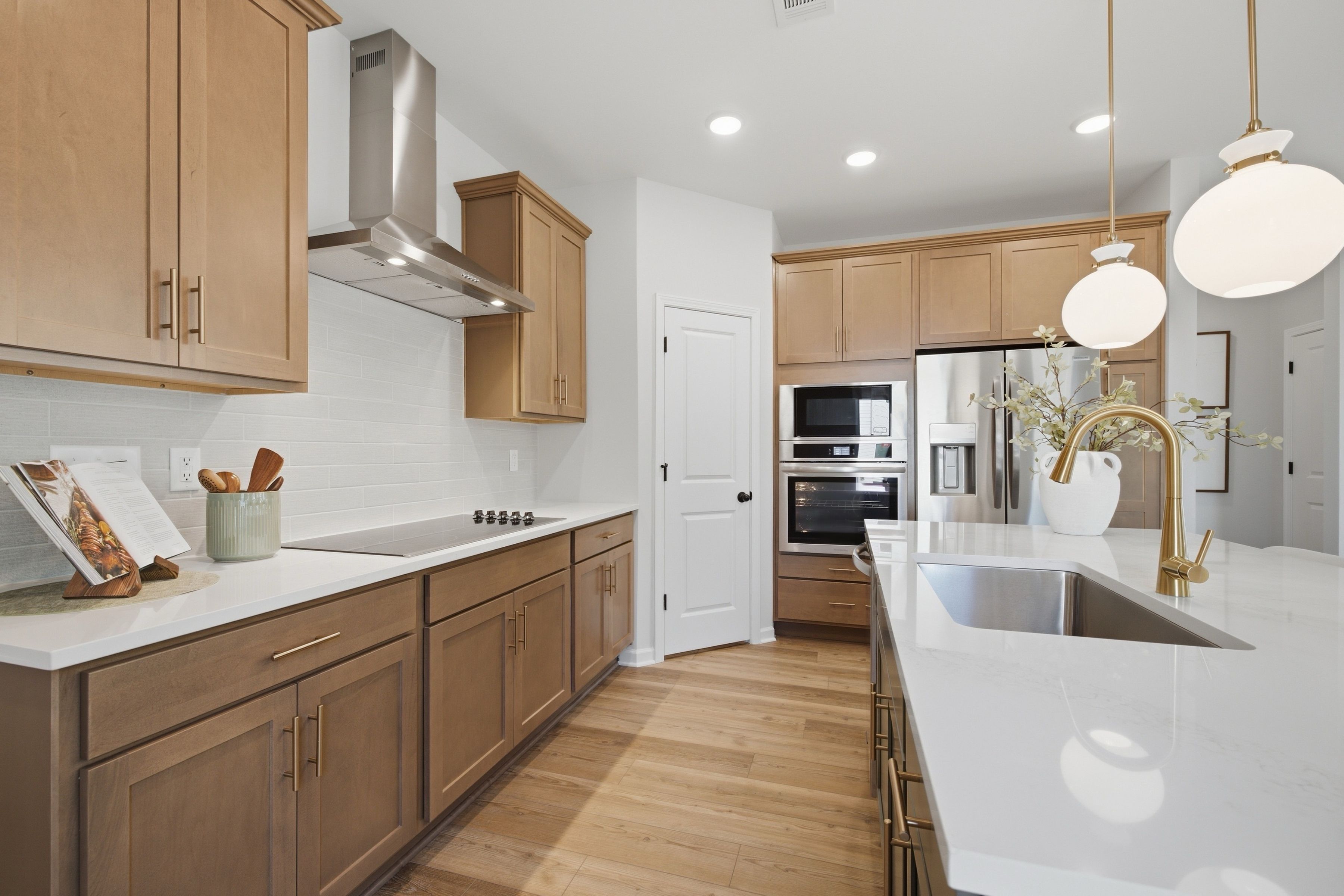 Modern kitchen at Greene Farm in Cartersville, Georgia by Davidson Homes with white quartz island, wood cabinets, gold pendant lights