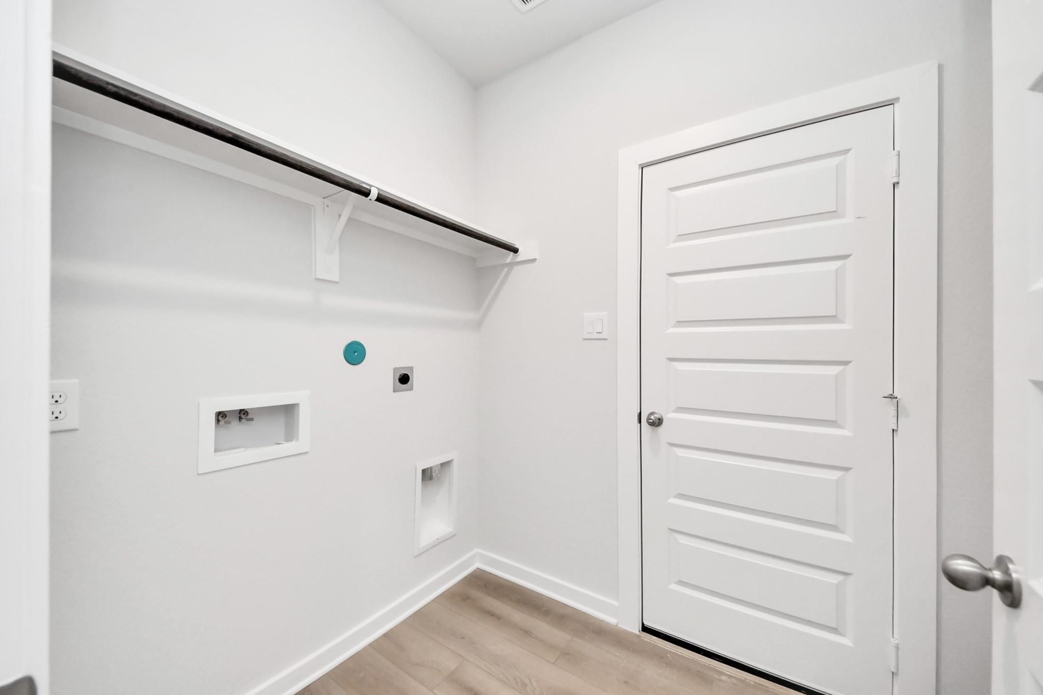 Laundry room with utility hookups and storage shelf in The Frio F floor plan at Liberty Estates, Cleveland, Texas.