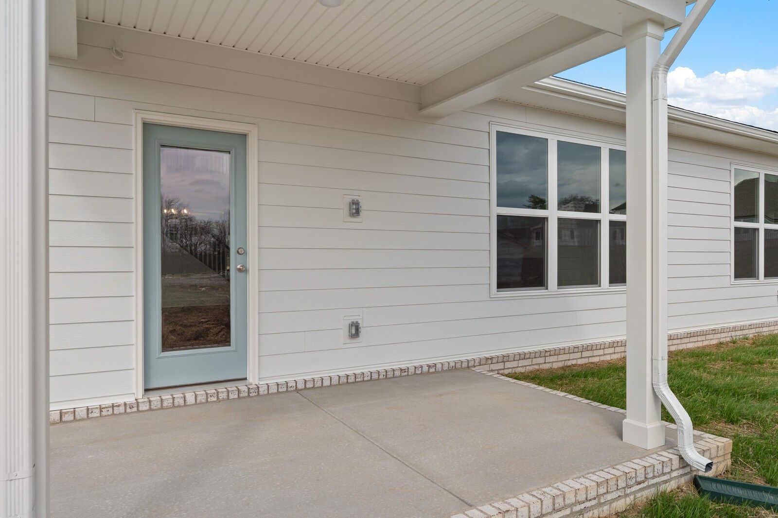 Covered back patio with glass French door, large windows, and white siding on Davidson Homes The Ridgeport in Gallatin, TN
