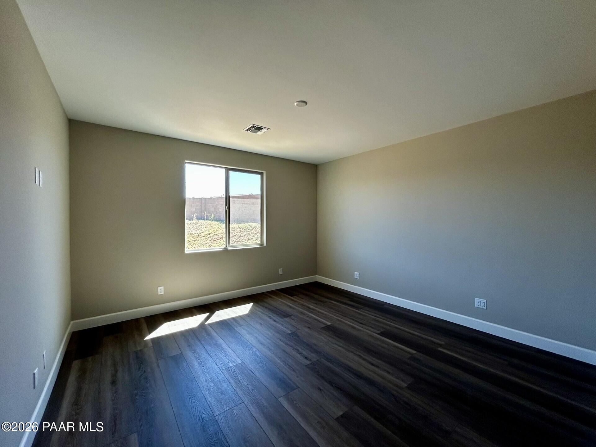 Bright, spacious bedroom with dark wood-style flooring in The Harmony C floor plan at Pronghorn Ranch, Prescott Valley.