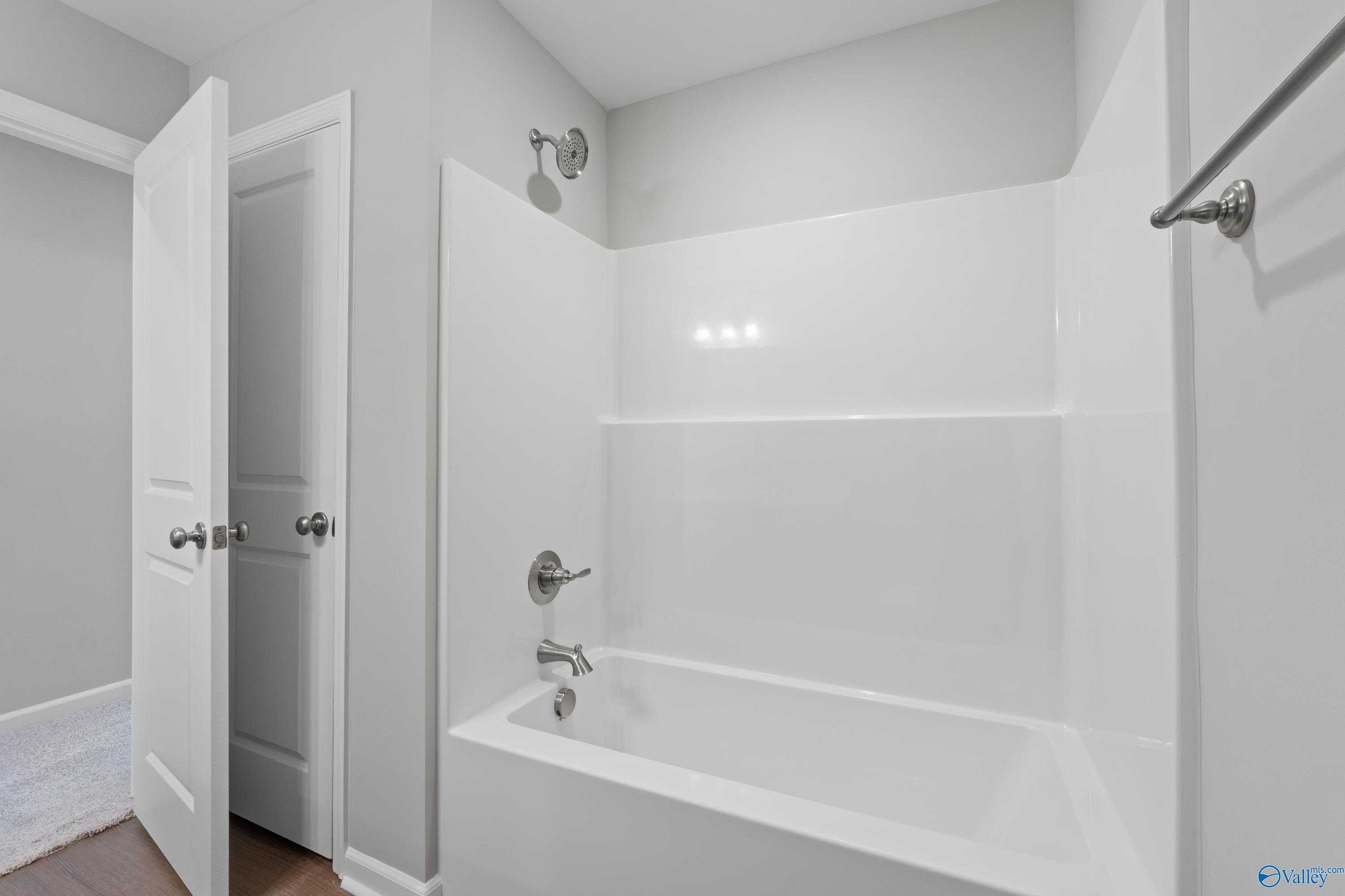 Modern bathroom with white tub, glass shower enclosure, chrome fixtures, and gray walls in Davidson Homes The Dorado, Athens, Alabama