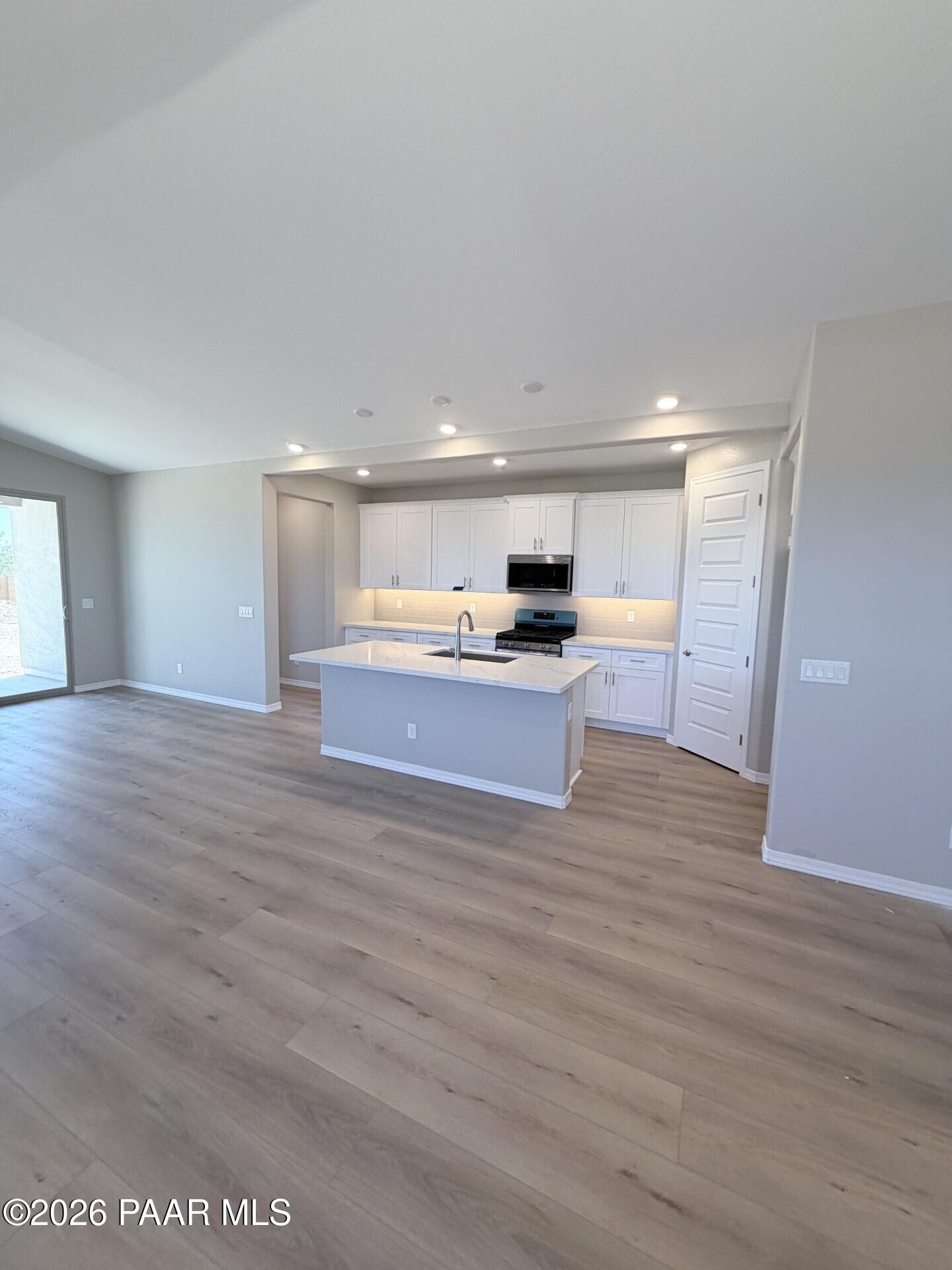 Open-concept kitchen with white cabinets, island, and wood-look flooring in The Frontier A home at Pronghorn Ranch, AZ.