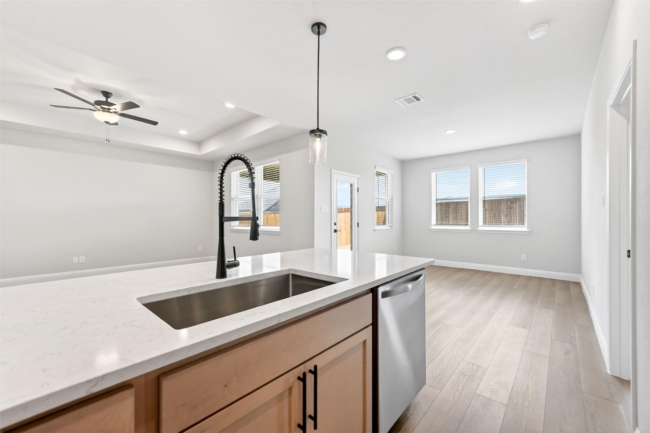 Modern kitchen with white quartz island, stainless steel sink, and open layout in The Holly C floor plan, Anna, Texas.