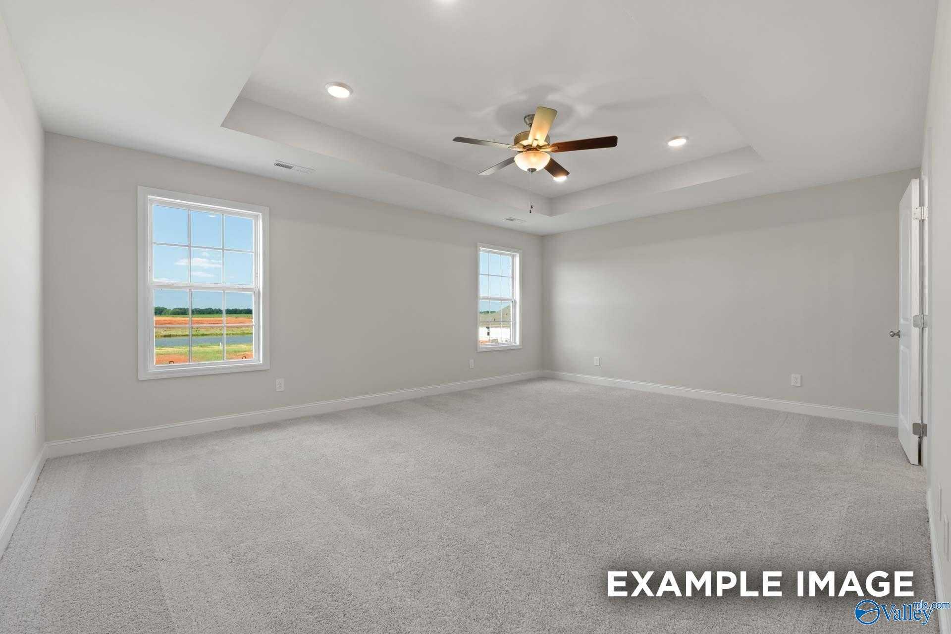 Spacious empty bedroom with ceiling fan, recessed lights, and large windows overlooking green fields in Davidson Homes The Madison A, Meridianville, Alabama