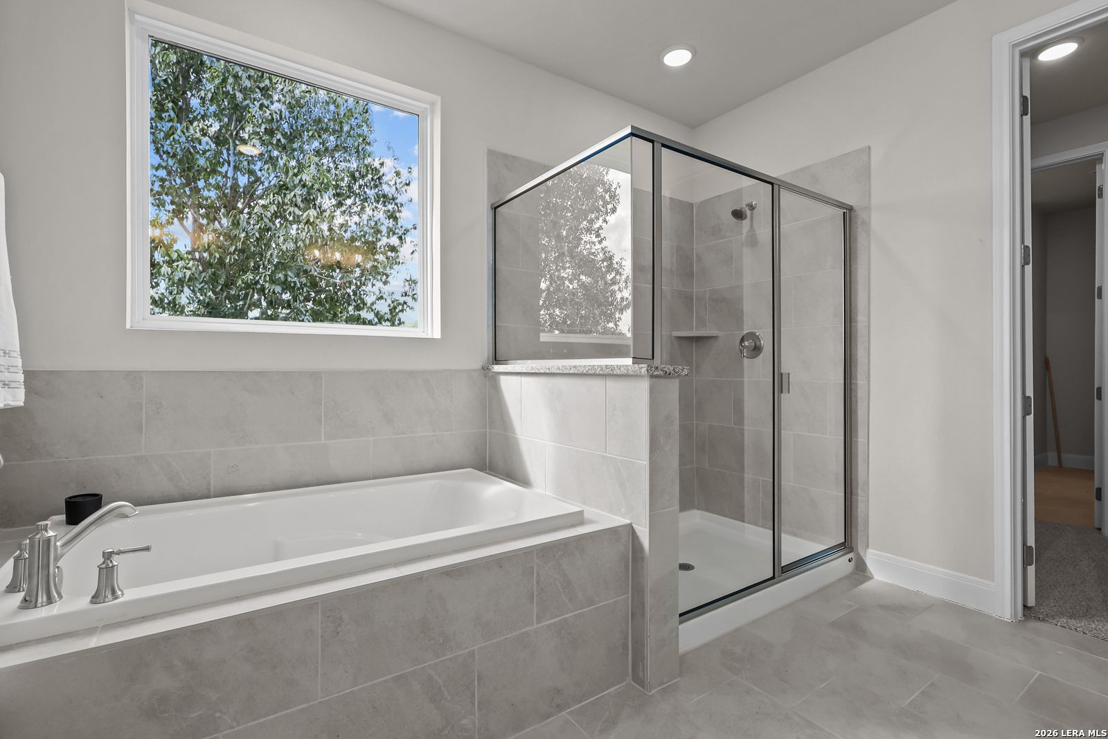 Modern primary bathroom with soaking tub and tiled glass shower in The Lanier H floor plan at Ladera, San Antonio, Texas.