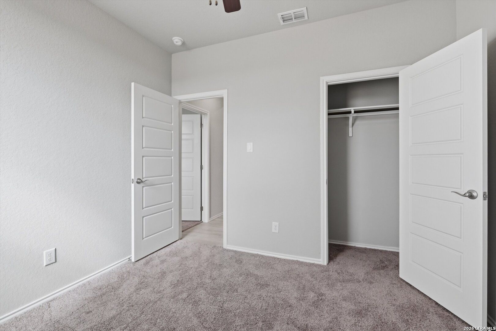 Secondary bedroom with open closet doors, ceiling fan, and gray walls in Davidson Homes The Frio B, Agave, San Antonio