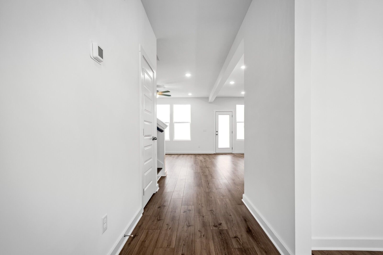 Bright open hallway with wood-style flooring leading to living area in The Willow floor plan at Calista Farms, White House.