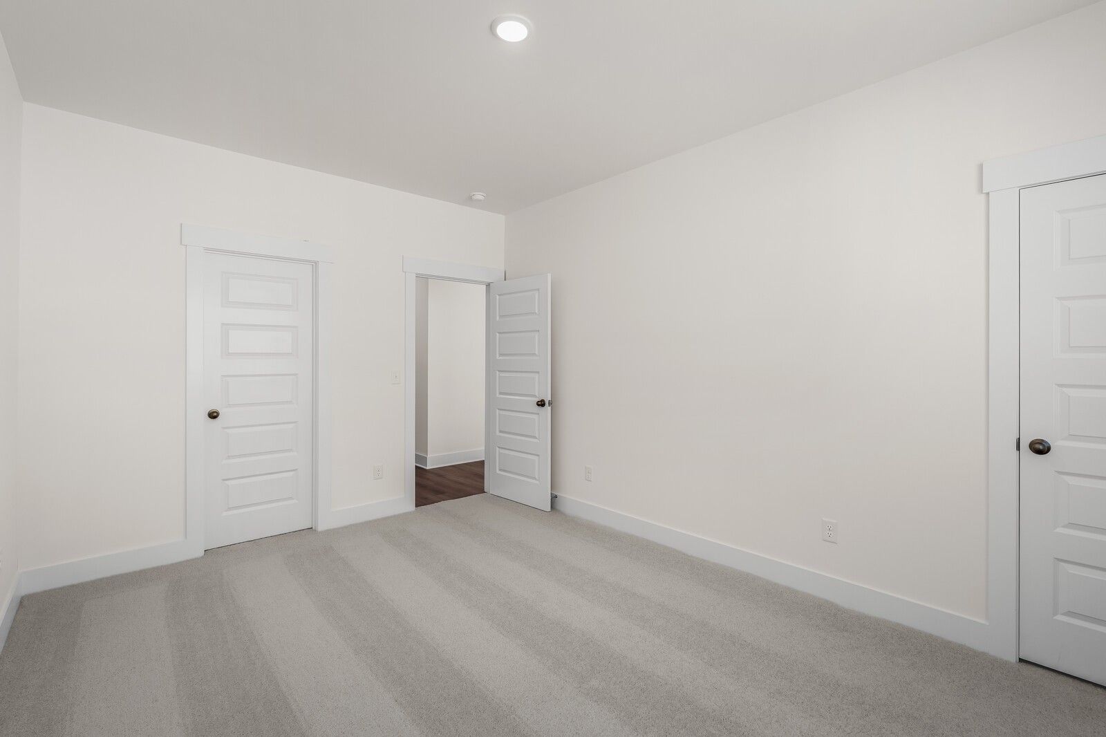 Spacious secondary bedroom with neutral carpet and white doors in The Willow floor plan at Woods Crossing, Gallatin, TN.