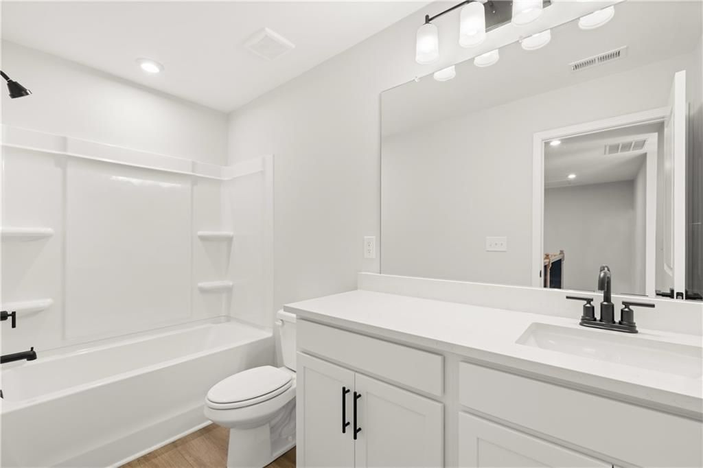 Bright white bathroom with tiled walk-in shower, soaking tub, double vanity, and large mirror in Davidson Homes The Cary A, Winder, Georgia