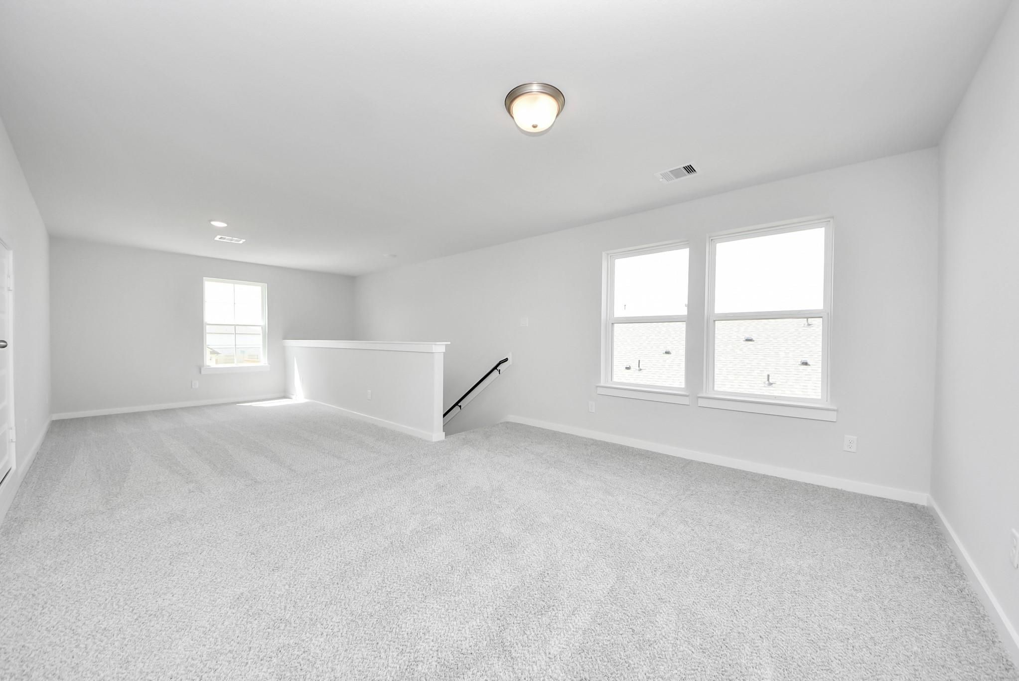 Spacious carpeted game room in The Verano B floor plan by Davidson Homes in Sunterra, Katy, Texas.
