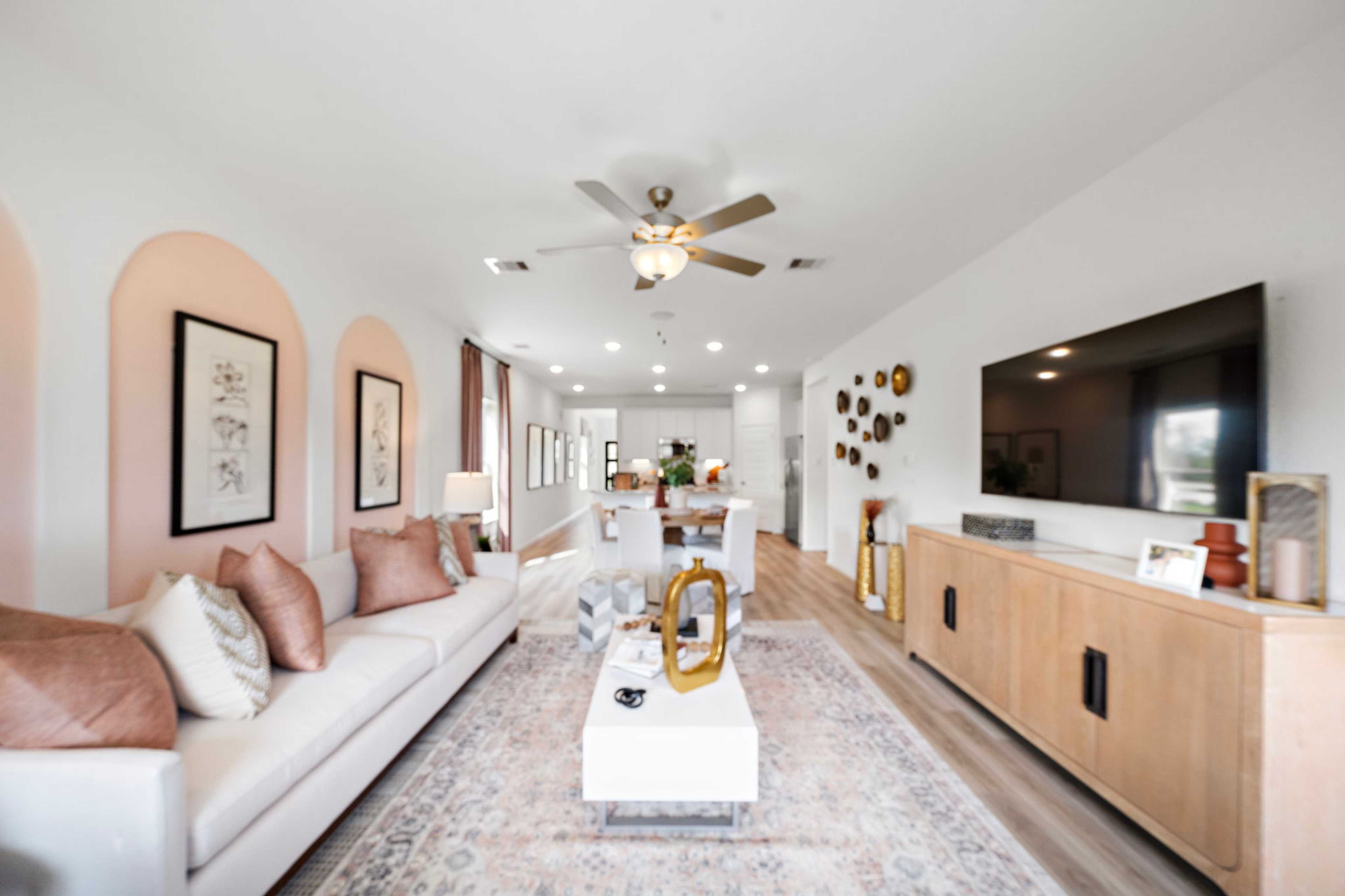 Spacious open-concept living room at The Villages at WestPointe in Dayton Texas with hardwood floors beige sofa pink accents and kitchen island