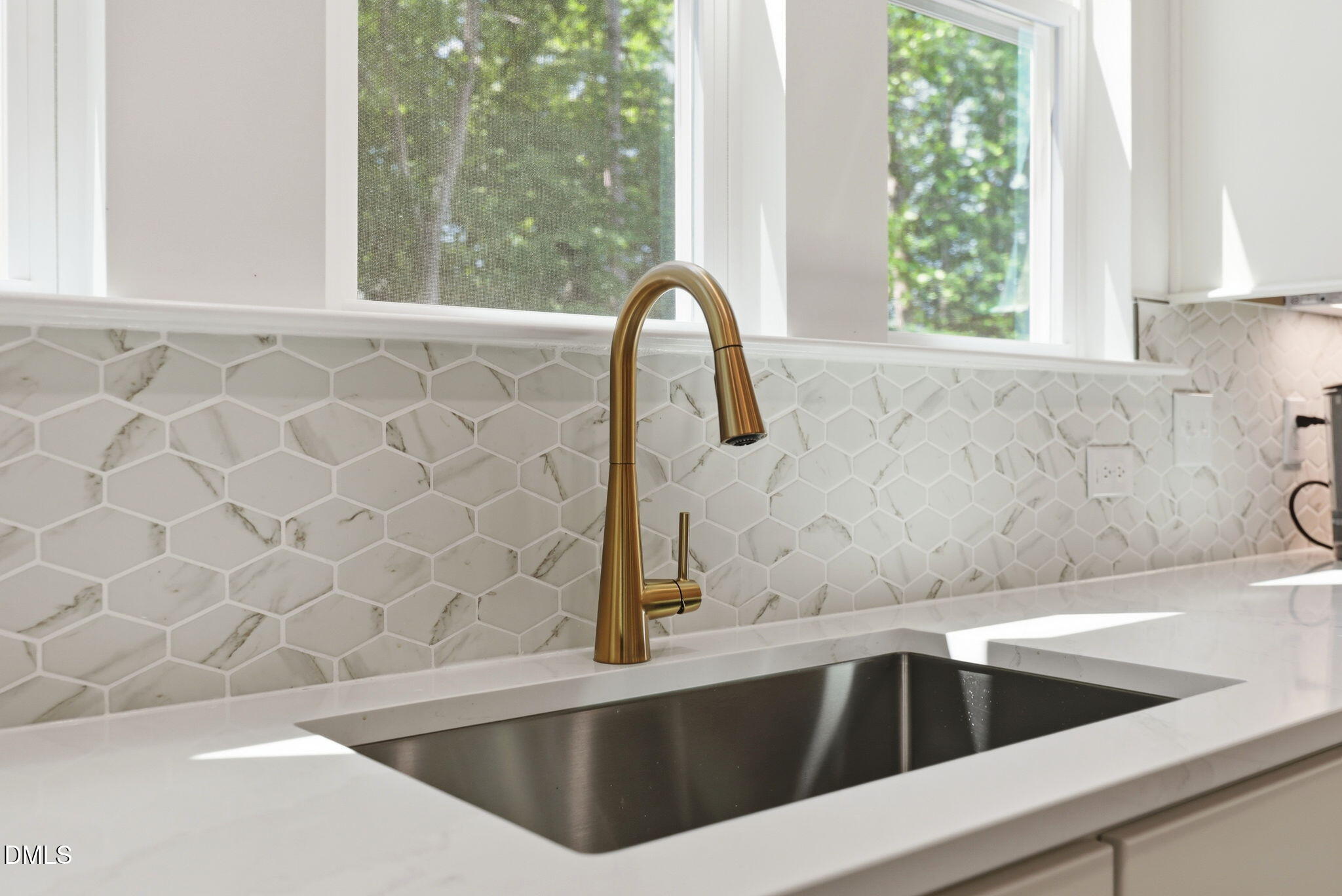 Gold gooseneck faucet with marble hexagon tile backsplash in The Aspen B floor plan at Wendell Ridge, North Carolina.