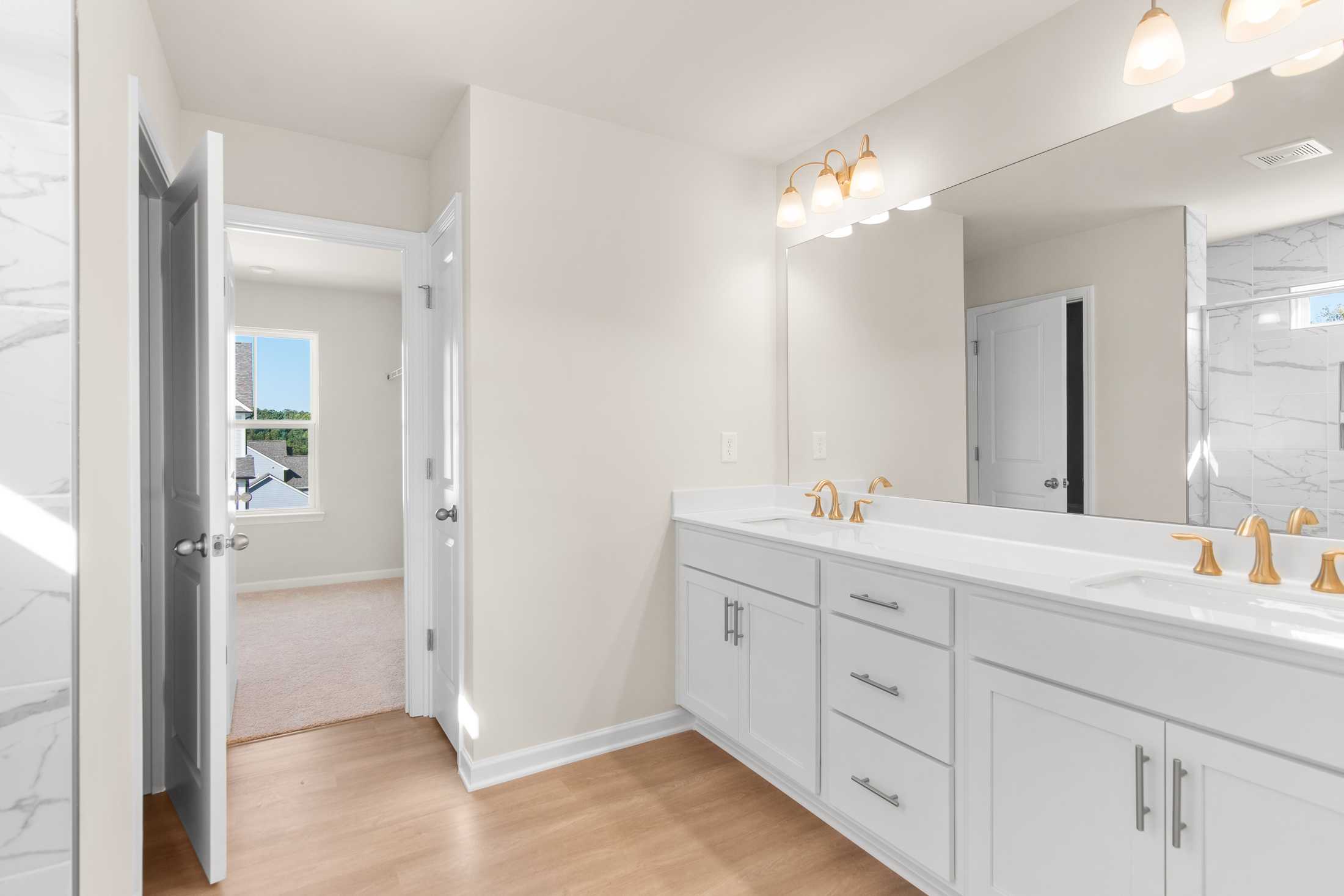 Spacious master bathroom in The Willow B featuring double vanity, gold faucets, marble counters, and walk-in shower
