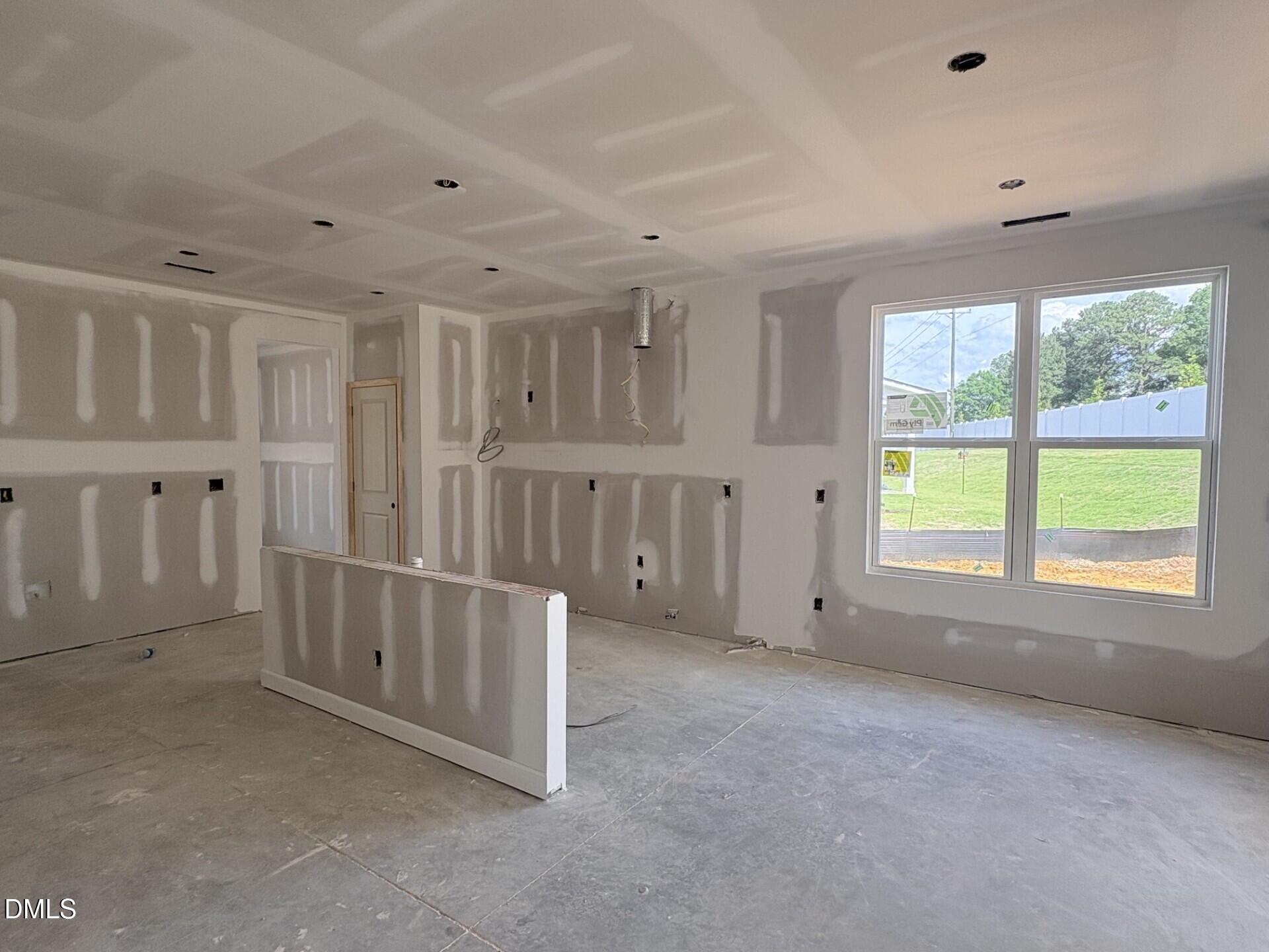 Unfinished kitchen area with drywall and island structure in The Ash C floor plan at Woodland Crossing, Zebulon, NC.