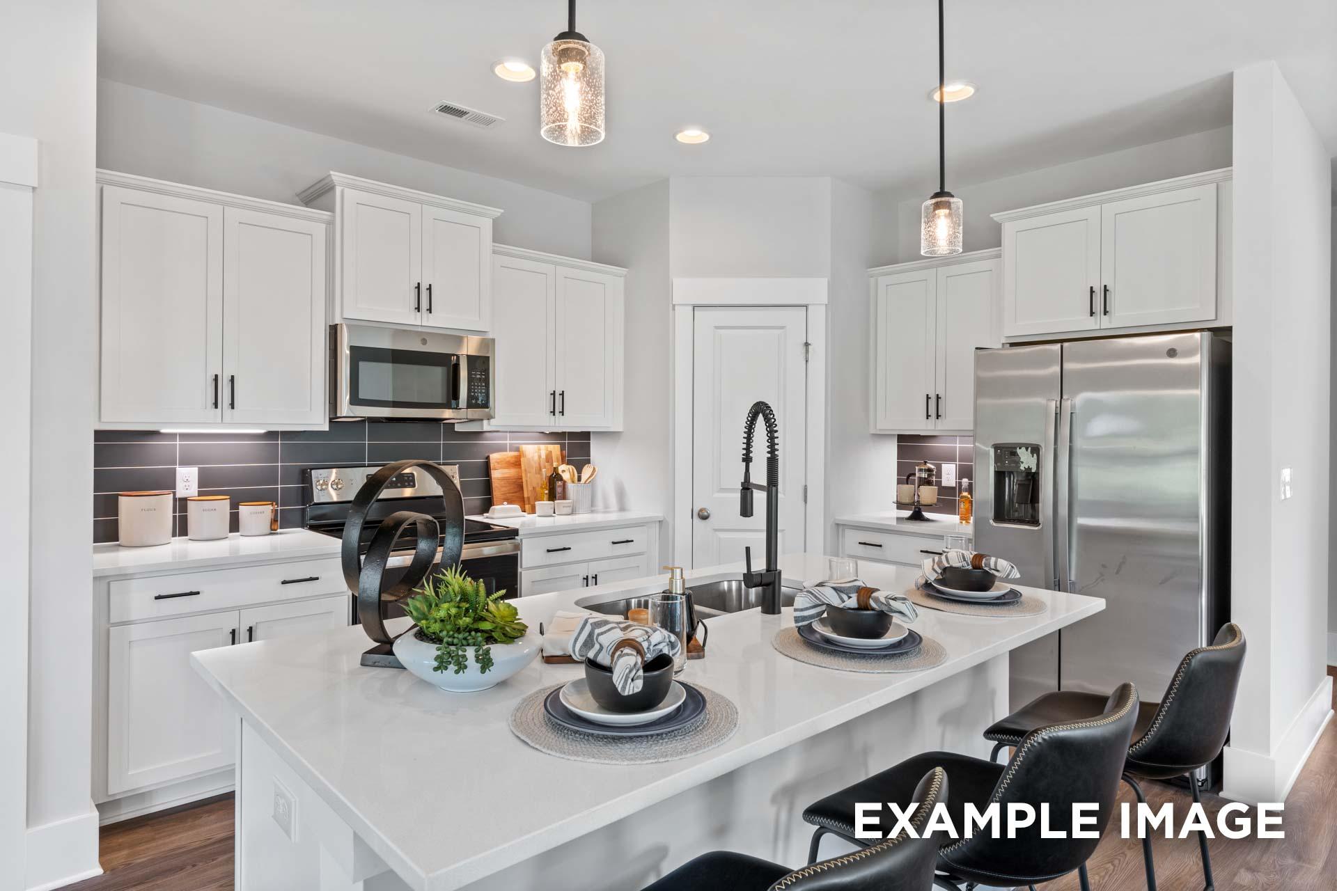 Spacious modern kitchen in The Franklin C with white shaker cabinets, quartz island, stainless appliances, and pendant lights