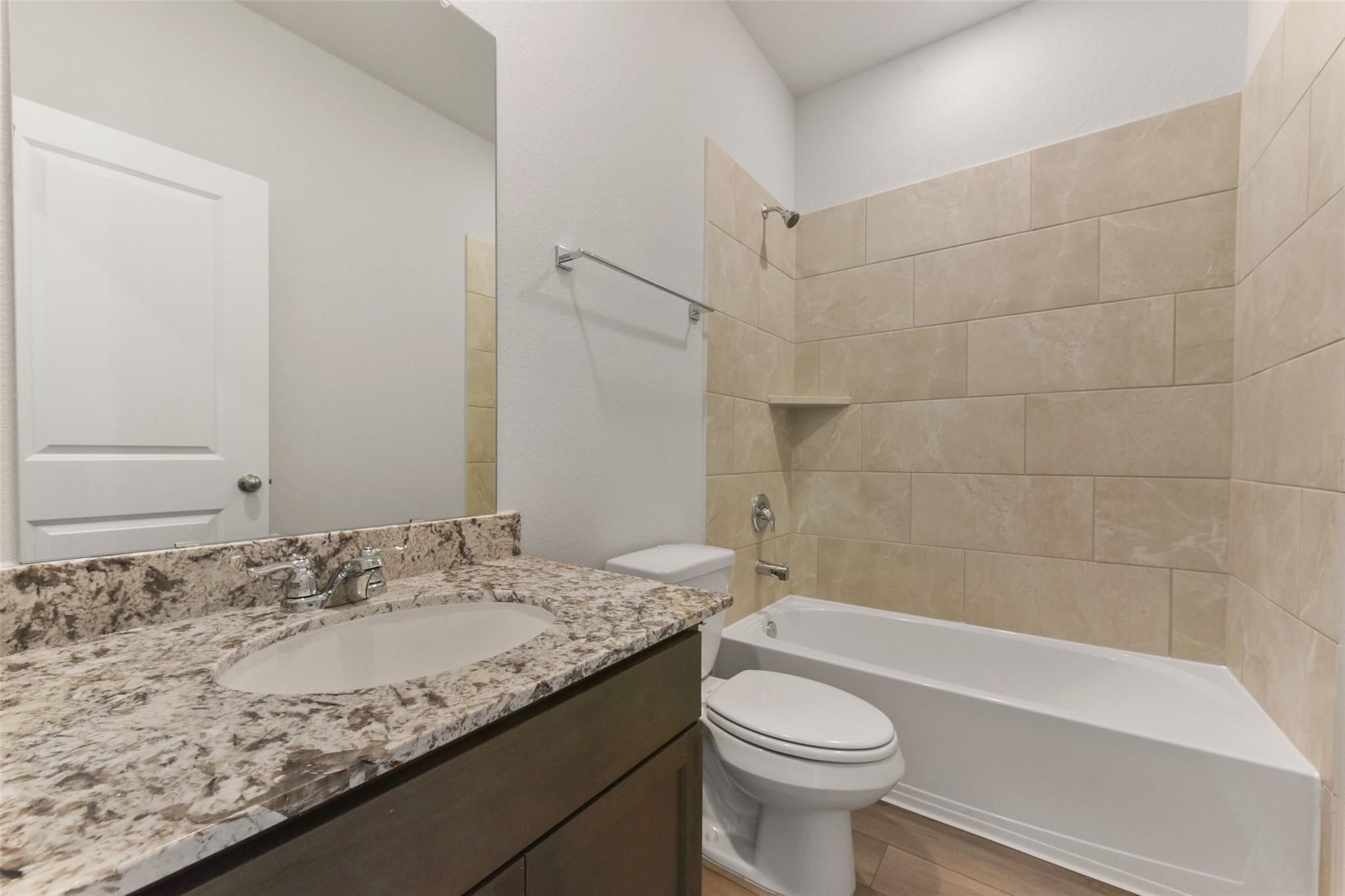 Modern bathroom with granite vanity, beige tiled shower, bathtub, and toilet in Davidson Homes The Laguna B, Magnolia, Texas