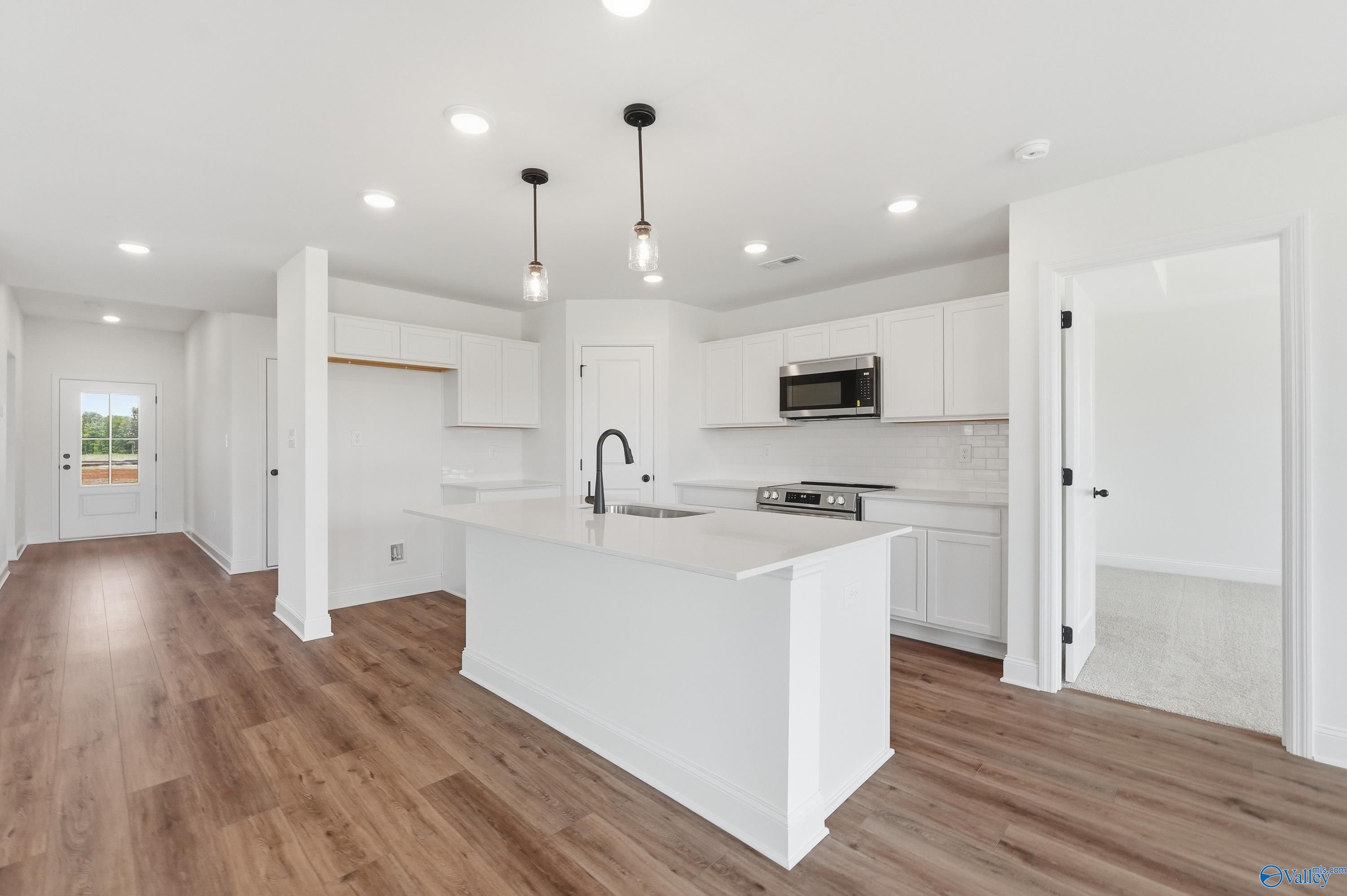 Modern kitchen with white island, pendant lighting, and stainless appliances in The Franklin at Heritage Lakes, New Market.