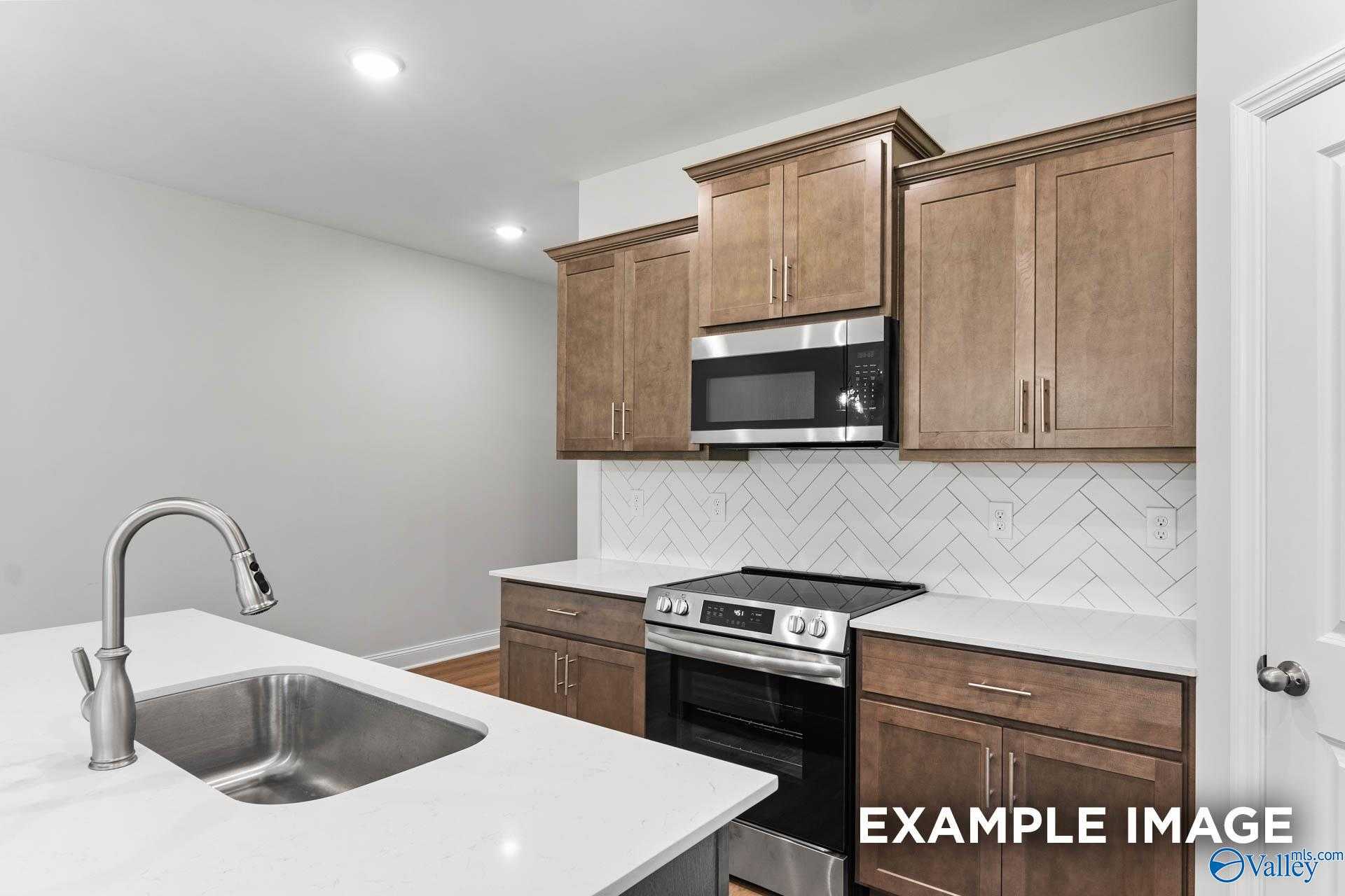 Modern kitchen with white quartz counters, stainless steel appliances, subway tile backsplash in Davidson Homes The Daphne C, Arab, AL