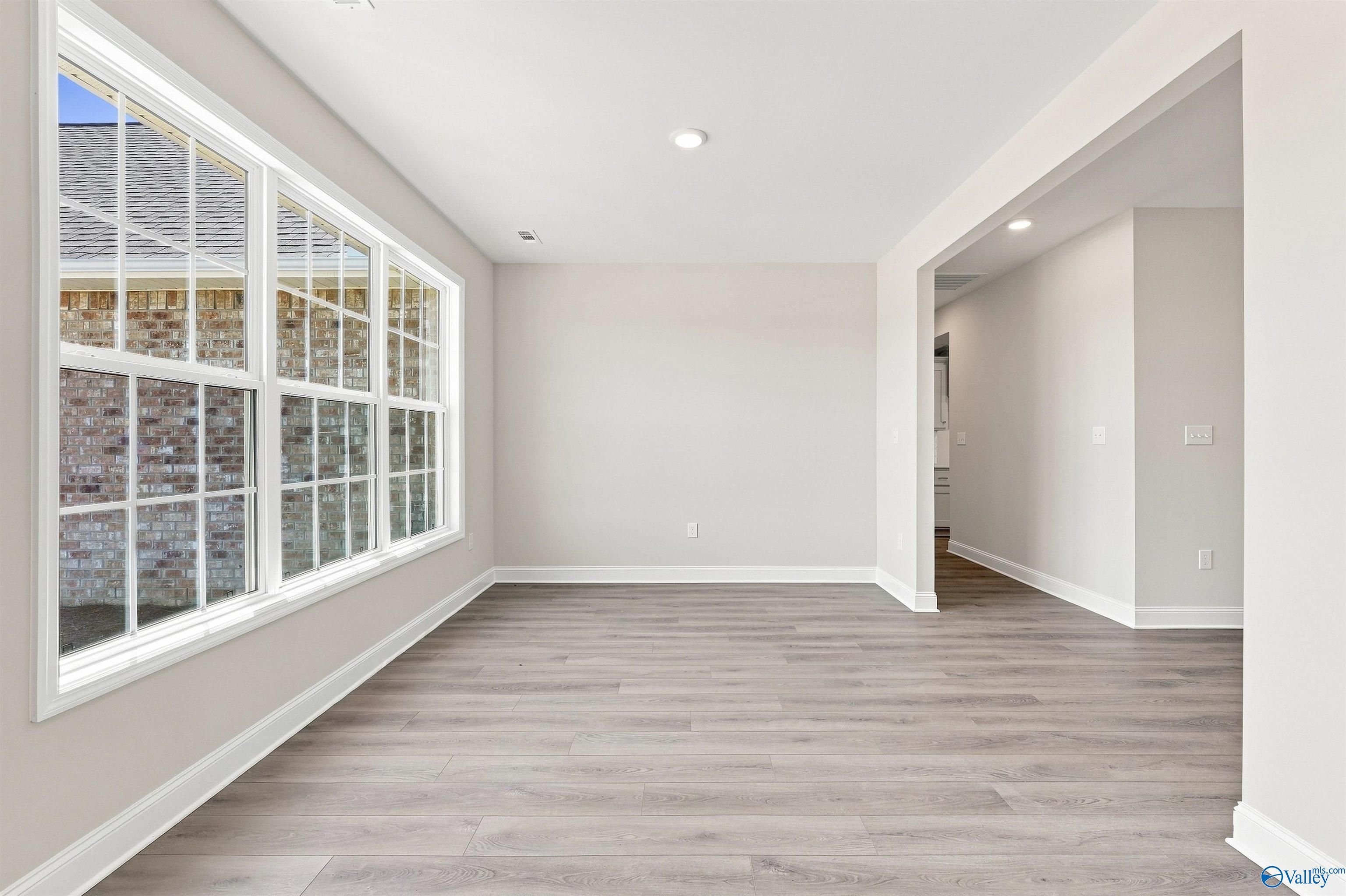Bright, open-concept dining area with wood-style flooring in The Oxford floor plan at Kendall Farms, Toney, Alabama.