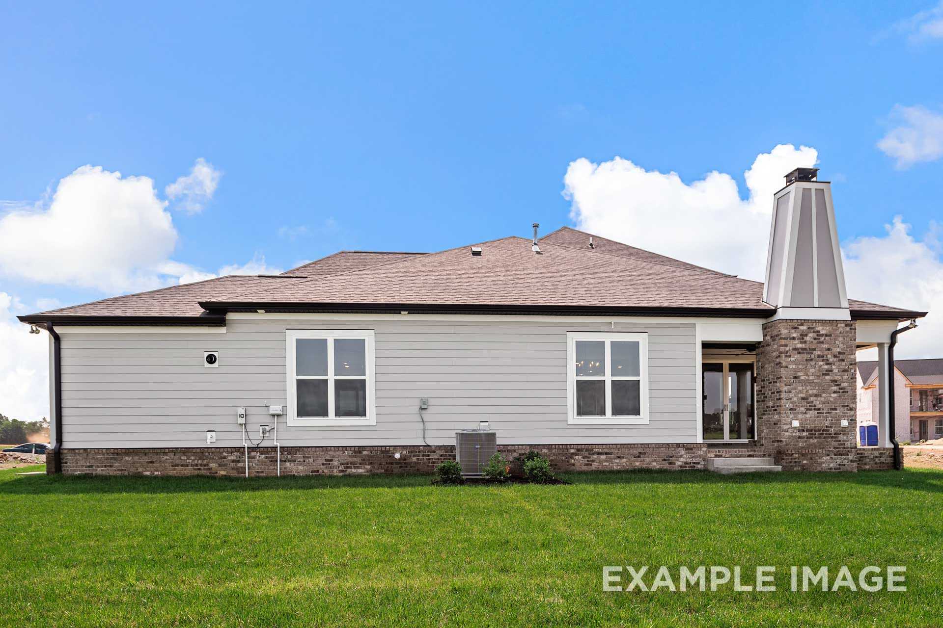 Side elevation of The Hathaway 2-story home with siding exterior, stone chimney, covered patio, and lush green lawn