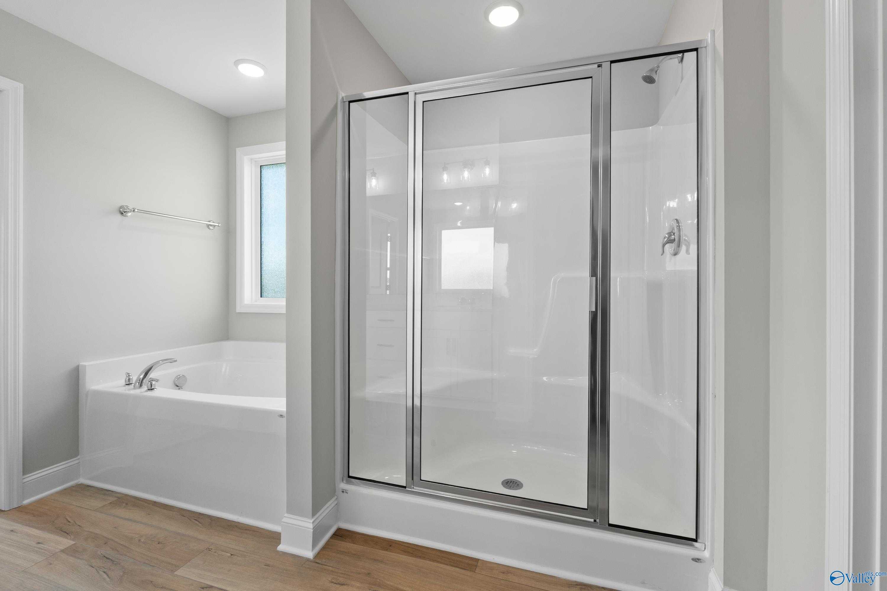 Elegant master bathroom with freestanding tub, frameless glass shower, and soft gray walls in Davidson Homes The Chelsea B, New Market, Alabama