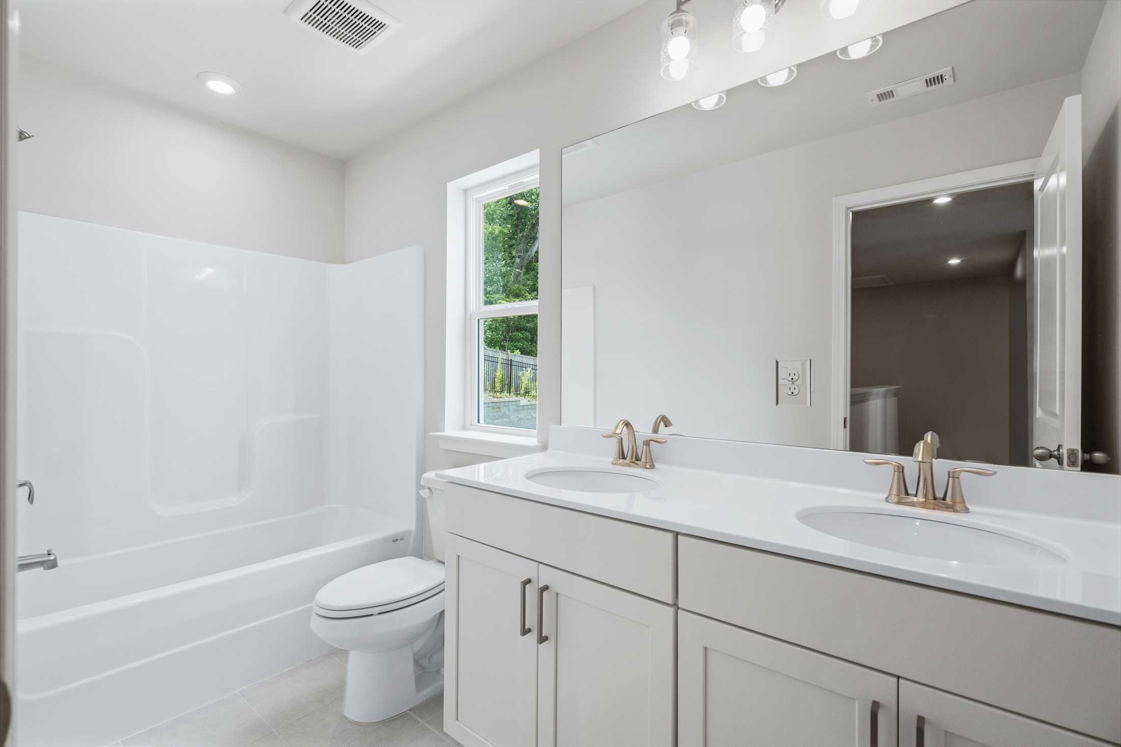Spacious master bathroom in The Cary A by Davidson Homes featuring double vanity, soaking tub, walk-in shower, and window