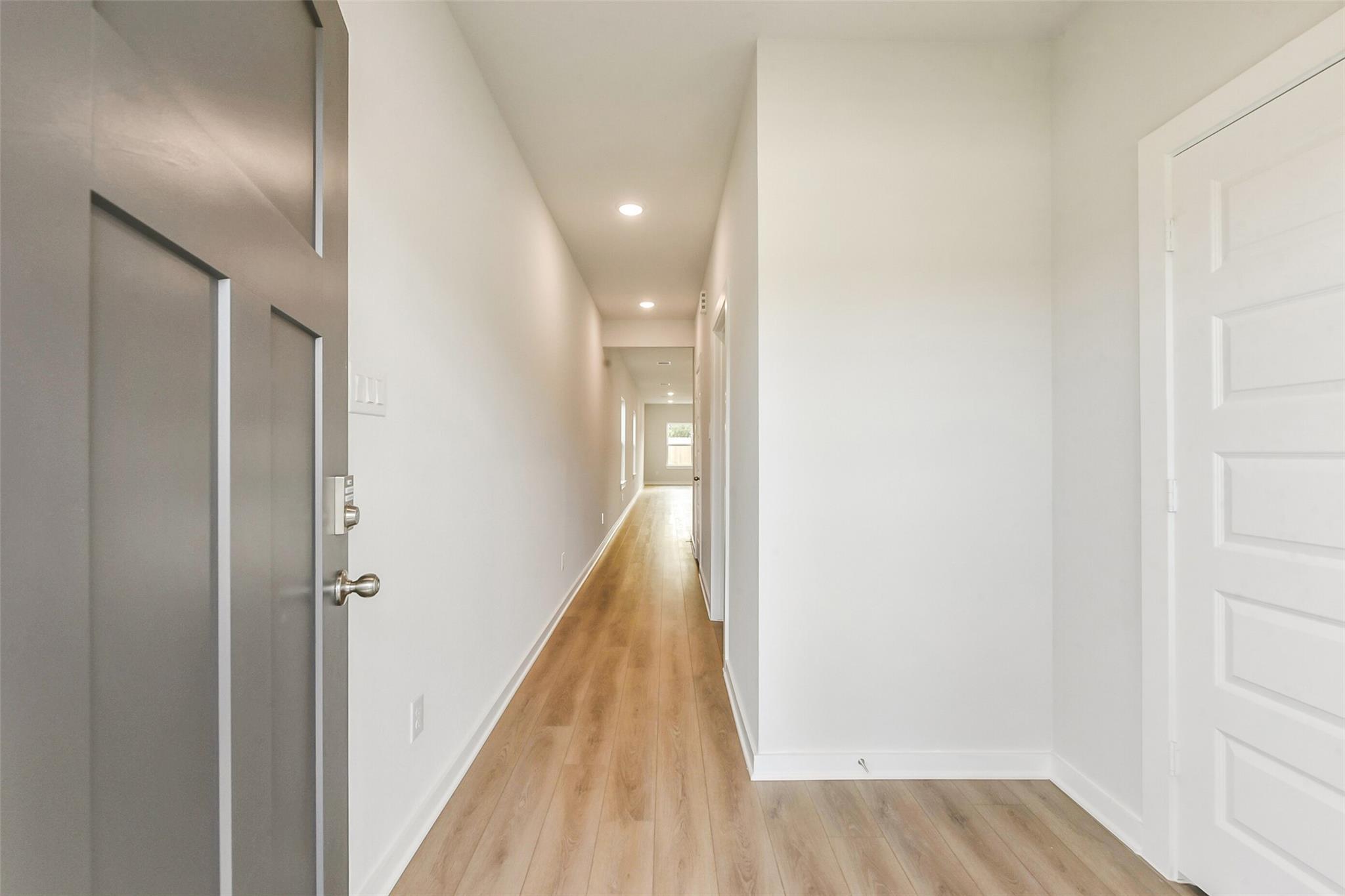 Bright entry hallway with white walls, light wood floors, and side doors in The Frio G home by Davidson Homes, Dayton, Texas