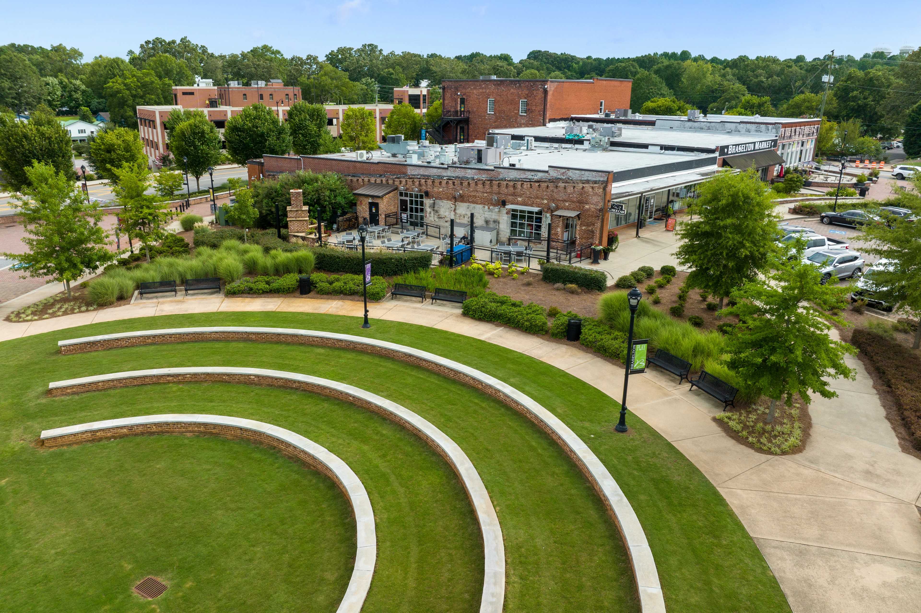 Aerial view of outdoor amphitheater at Wehunt Meadows in Hoschton Georgia with curved stone seating grassy lawn and brick pavilion