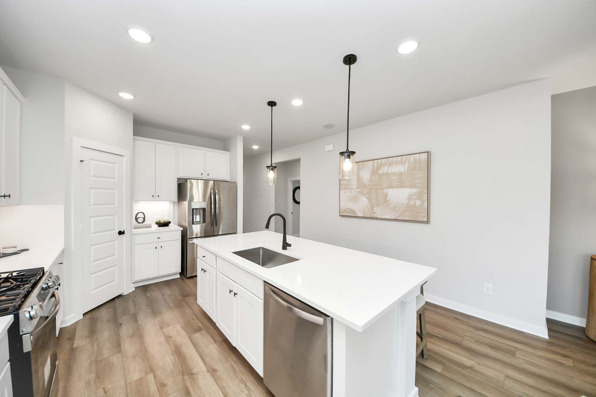 Modern kitchen with white cabinets, quartz island, and stainless steel appliances at Enclave at Newport in Crosby, Texas.