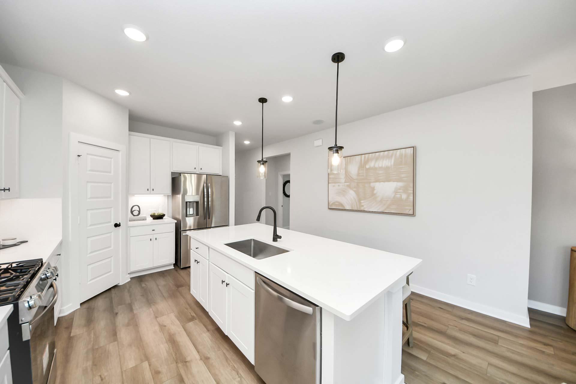 Modern kitchen with white cabinets, quartz island, and stainless steel appliances at Enclave at Newport in Crosby, Texas.
