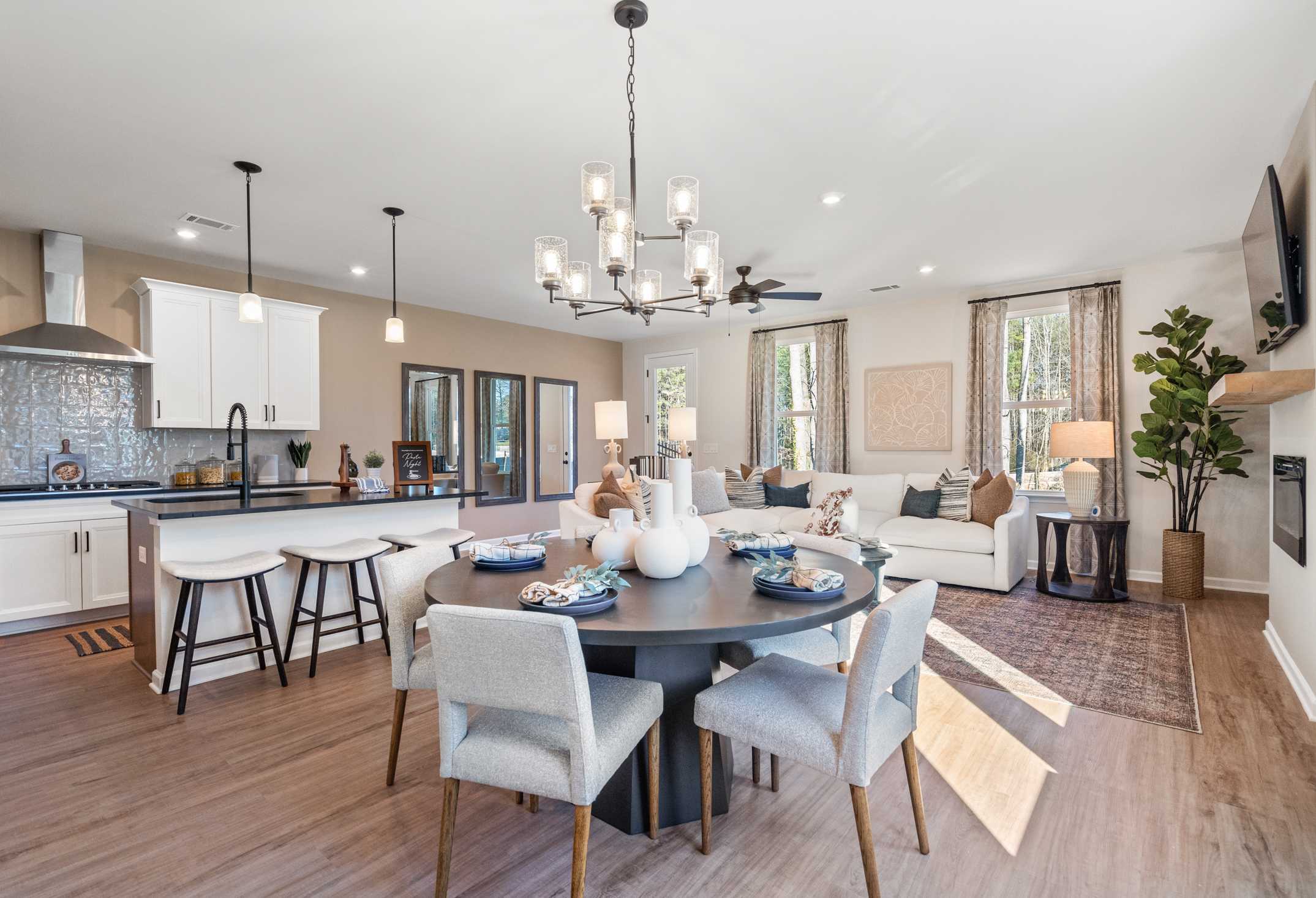 Open-concept kitchen and dining in The Marion A home, white cabinetry, subway tile backsplash, round table, bar stools, adjacent living area with fireplace