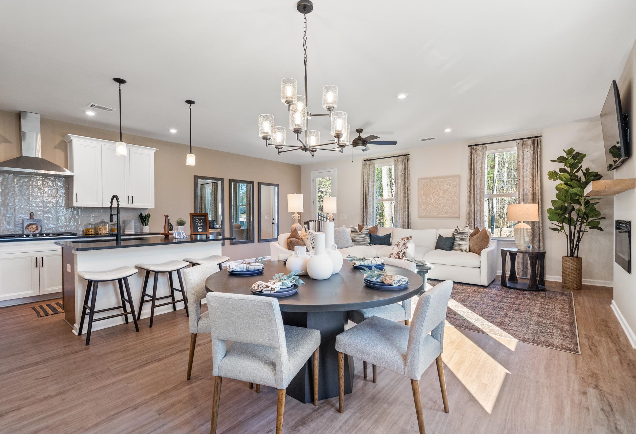 Open-concept kitchen and dining in The Marion A home, white cabinetry, subway tile backsplash, round table, bar stools, adjacent living area with fireplace