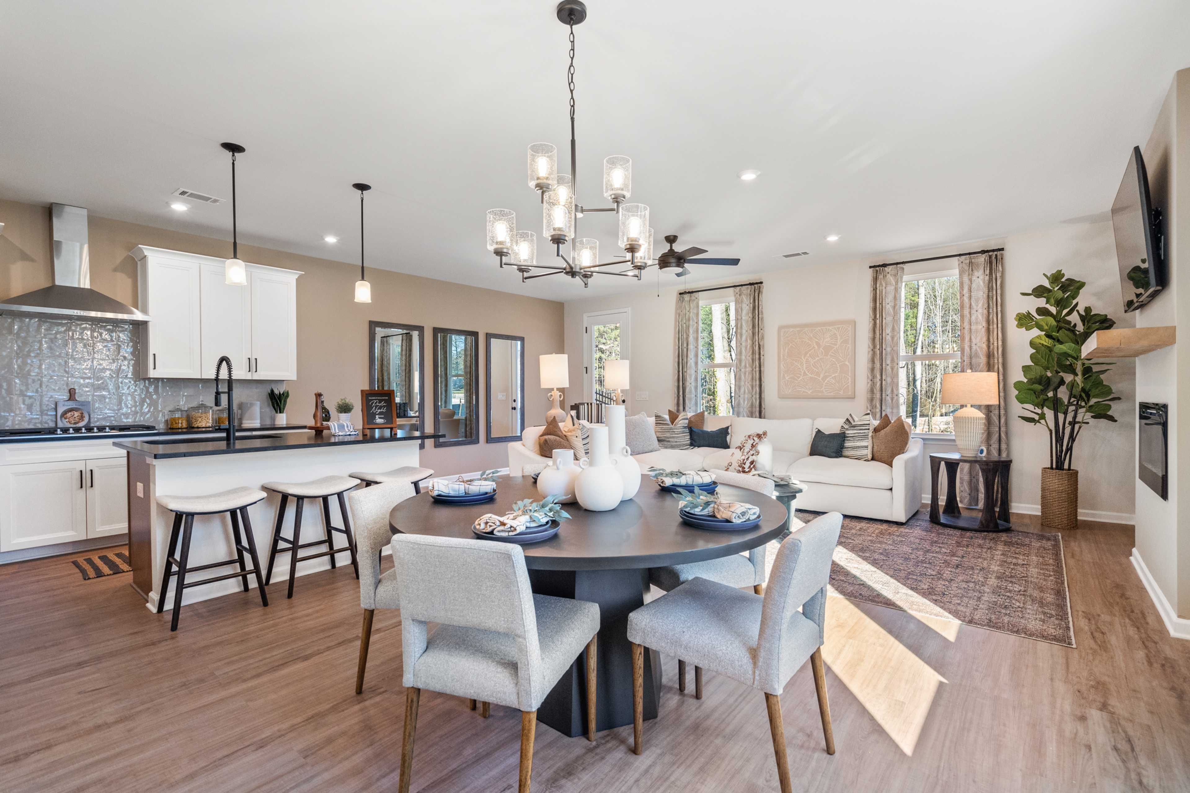 Open-concept kitchen dining living room at The Village at Shallowford in Kennesaw GA with white cabinets hardwood floors round table and fireplace