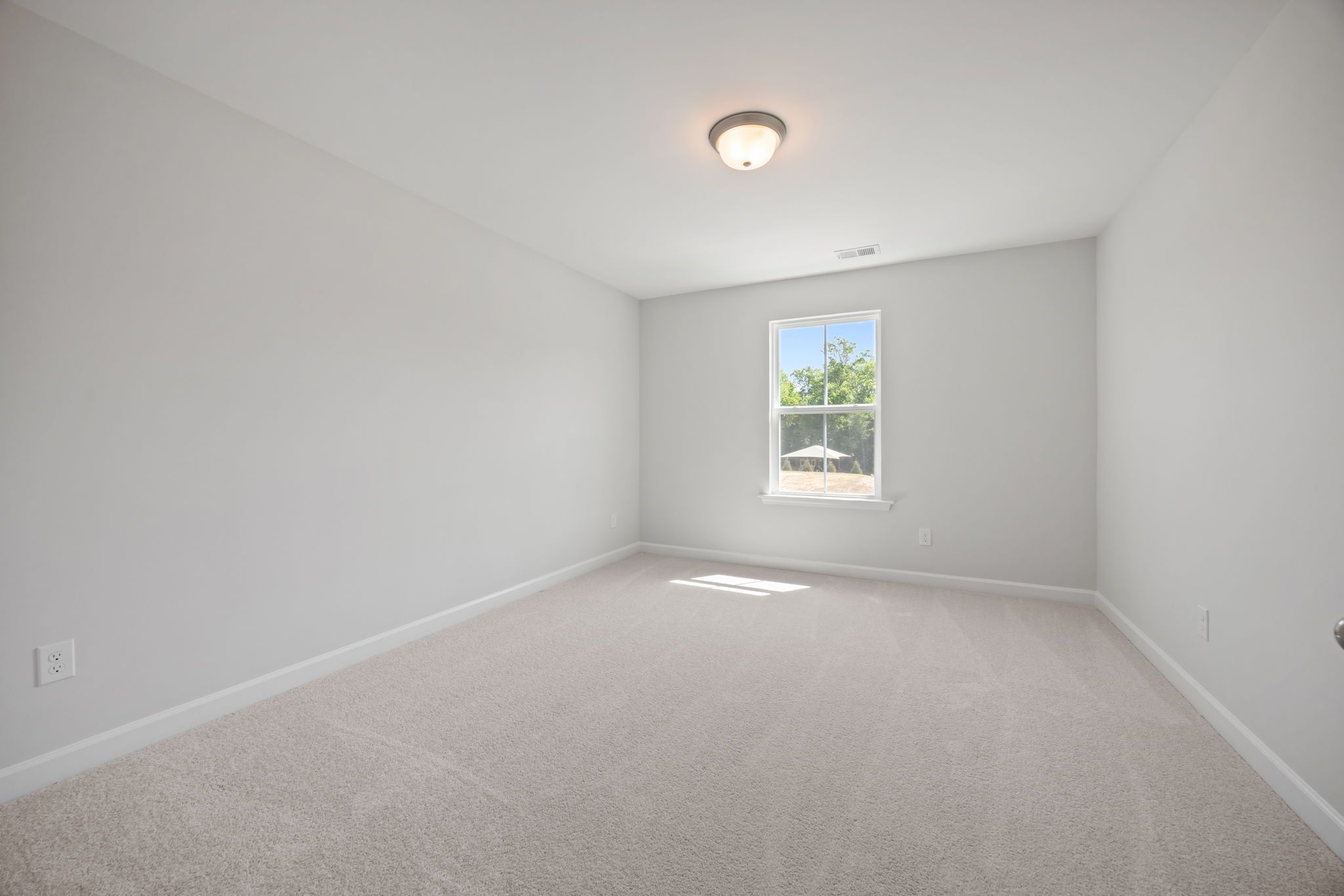 Bright, neutral secondary bedroom in The Ashport B floor plan featuring plush carpeting and natural light.