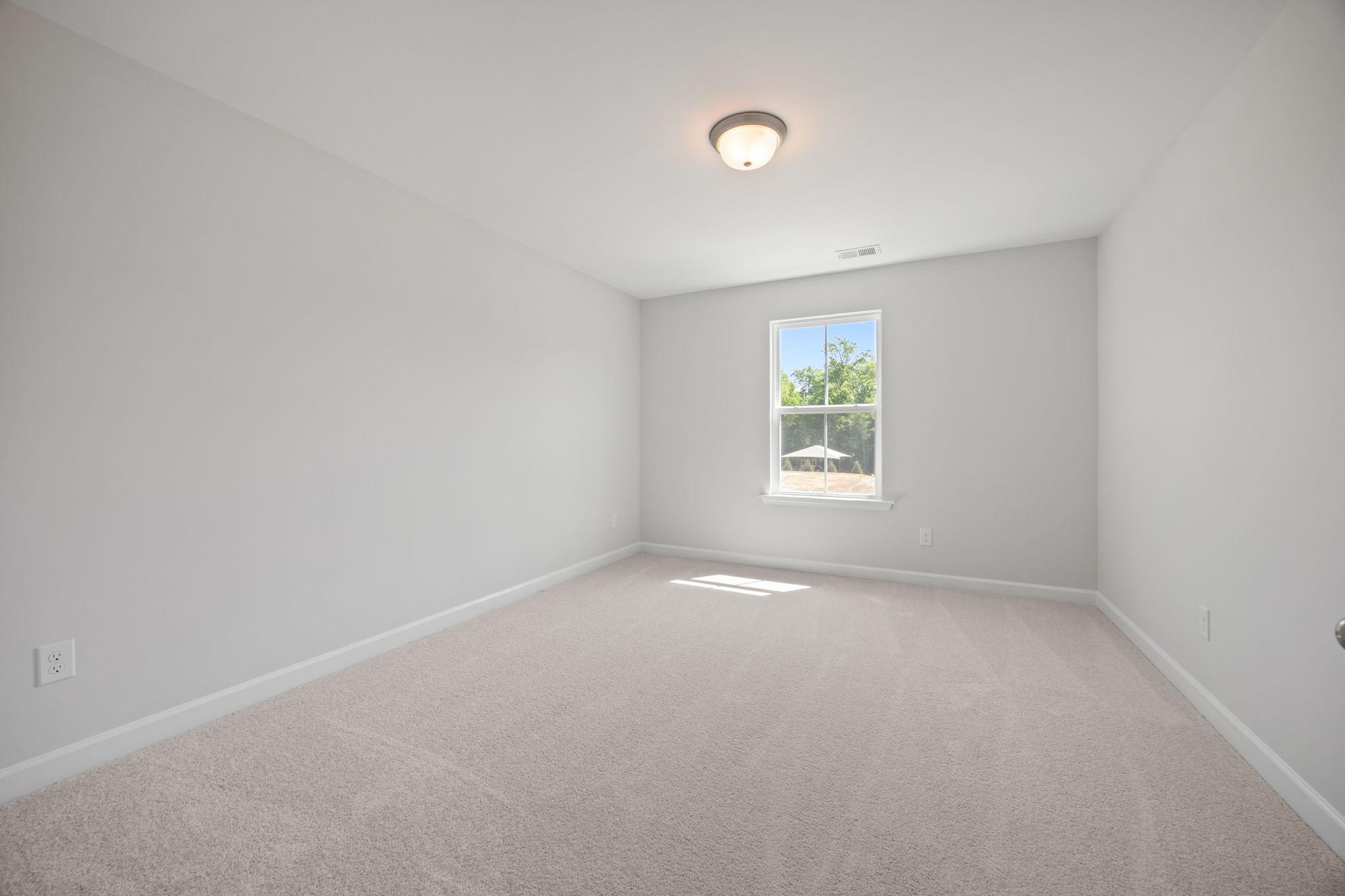 Bright, neutral secondary bedroom in The Ashport B floor plan featuring plush carpeting and natural light.