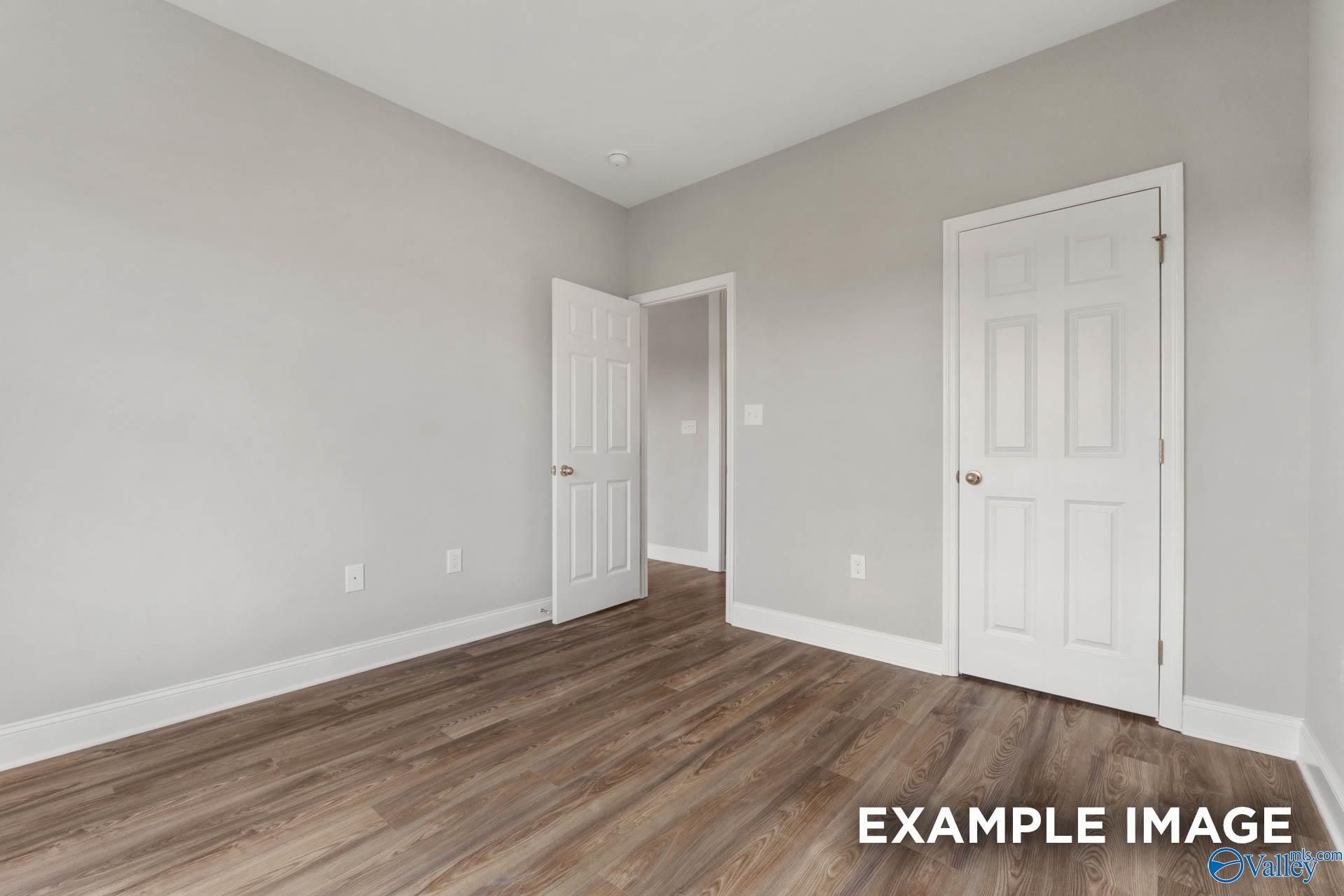 Bright secondary bedroom with light gray walls, white doors, and hardwood floors in The Shelby B, Athens, Alabama
